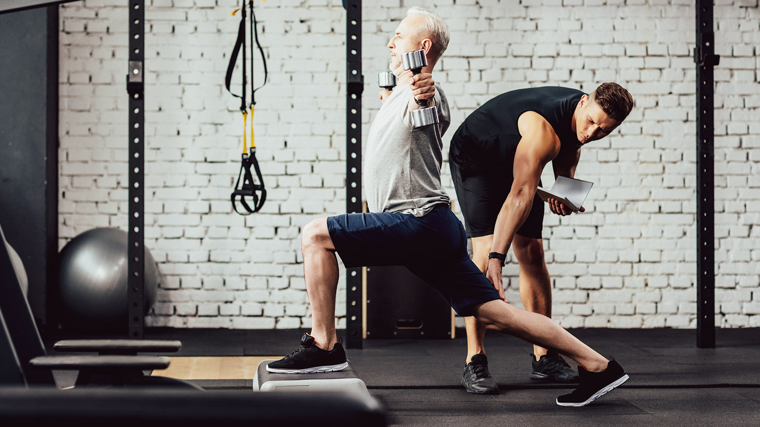 male trainer assisting older client