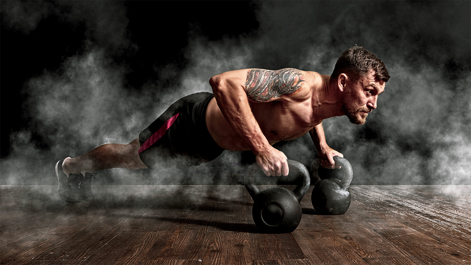 man doing pushup with kettle bells