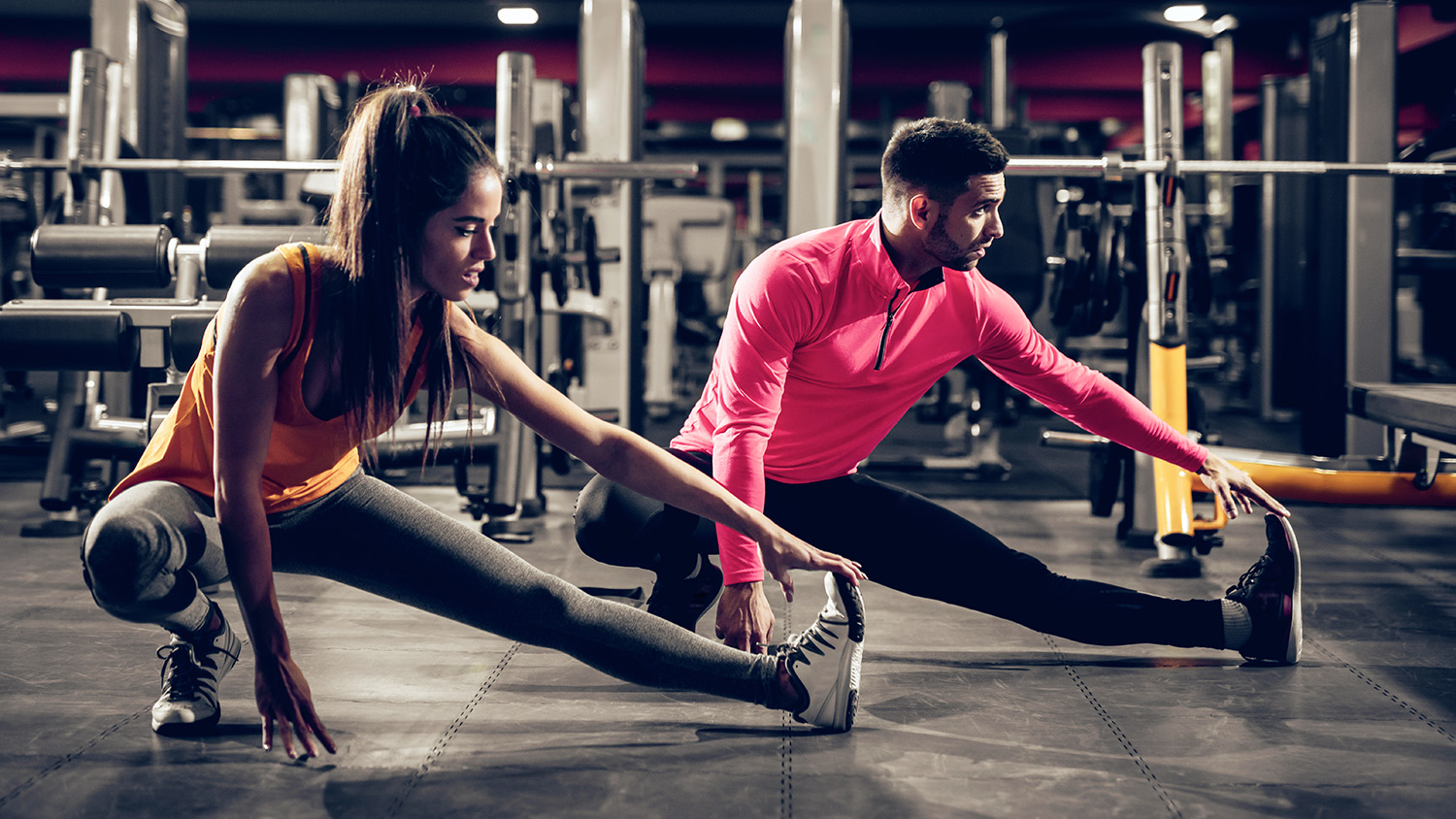 man and woman stretching at a gym