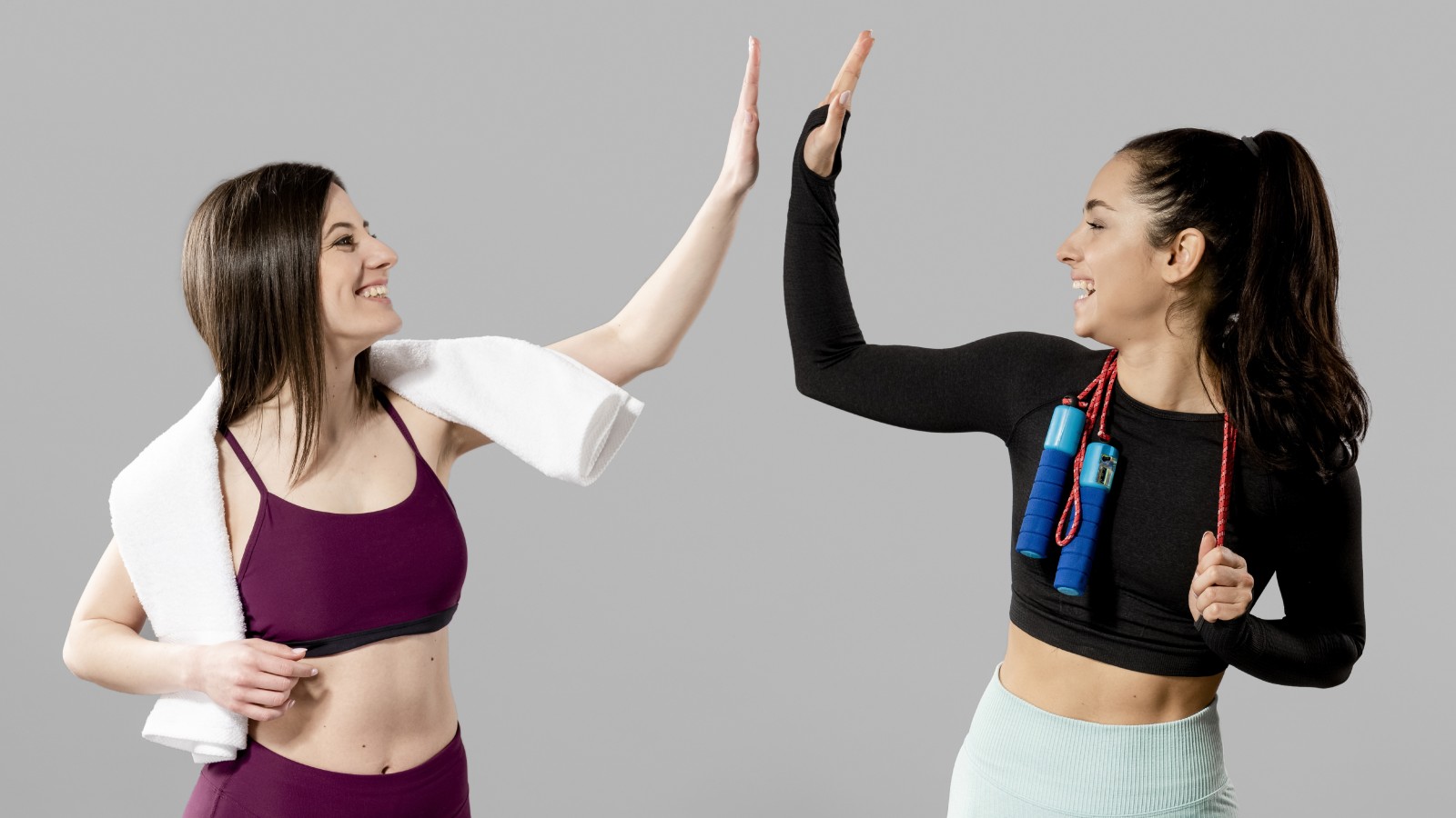 Two women in fitness attire doing a high five.