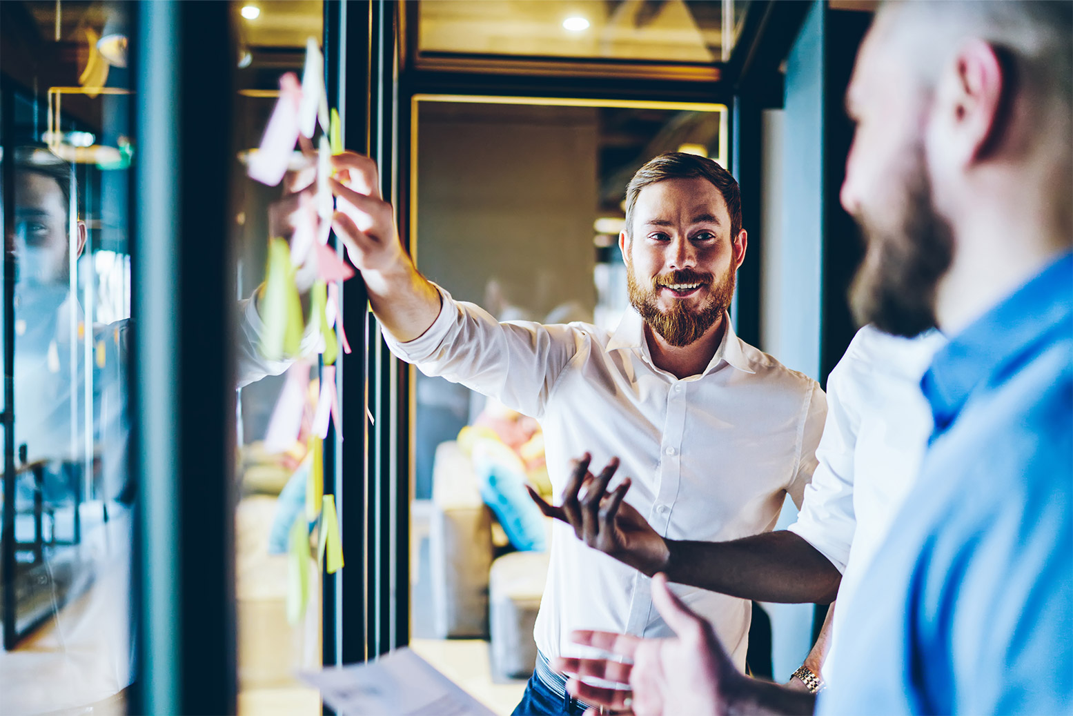 Marketing professionals discussing marketing and pointing at sticky notes while smiling