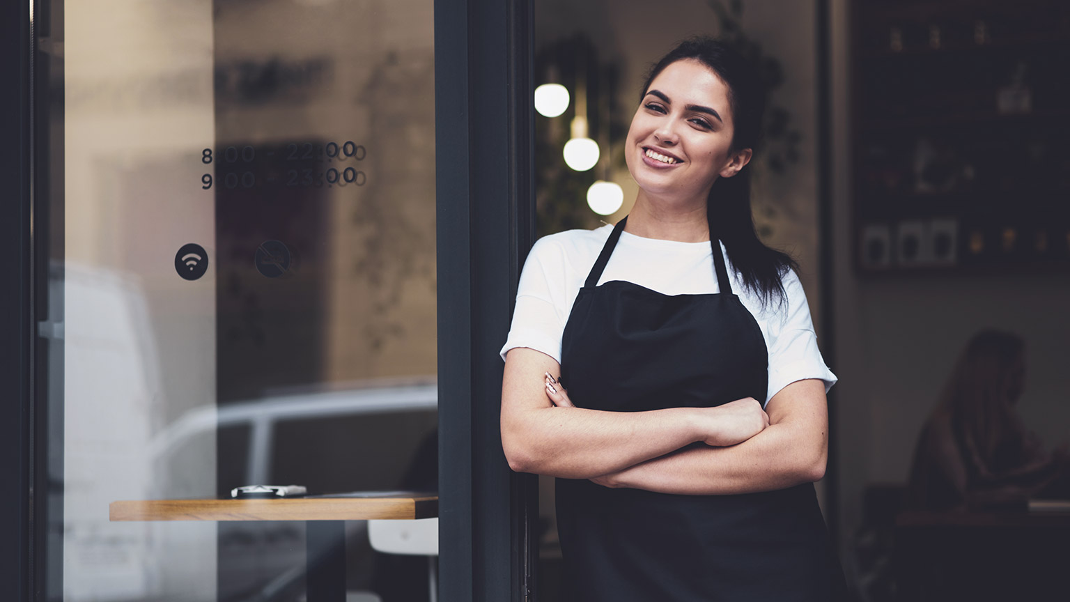 Happy woman standing outside her cafe