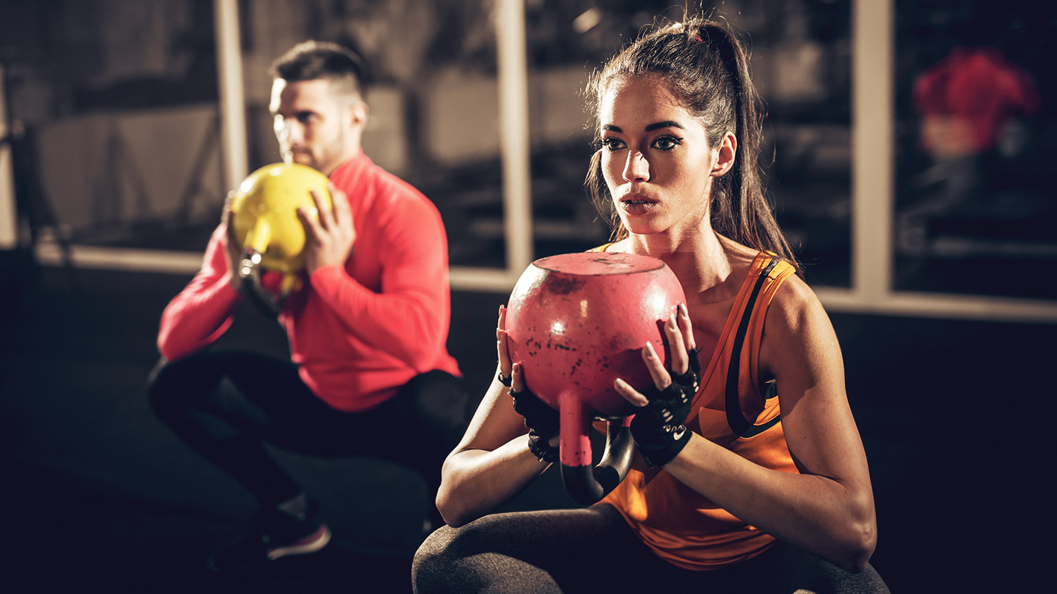 Couple working out in gym with kettle bells