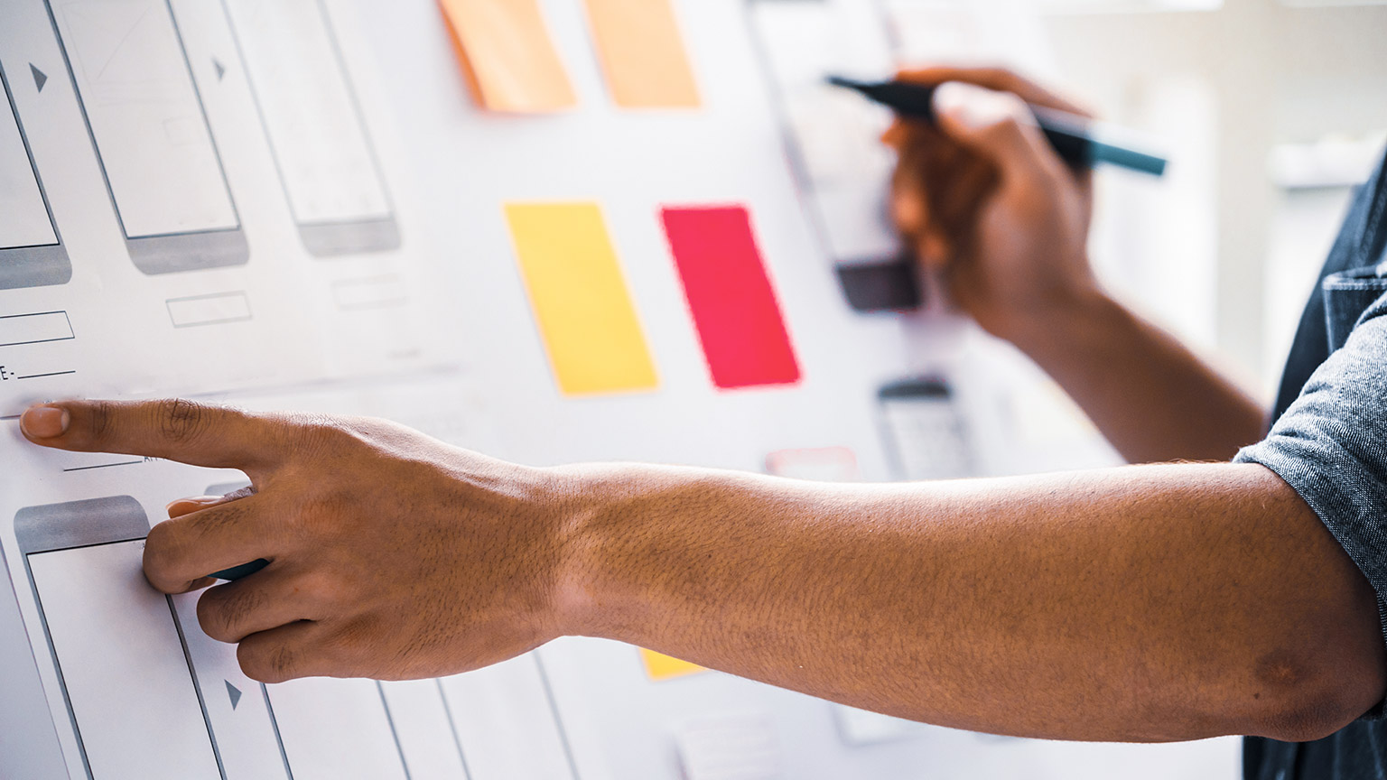 Man pointing at diagram on wall while working on app design