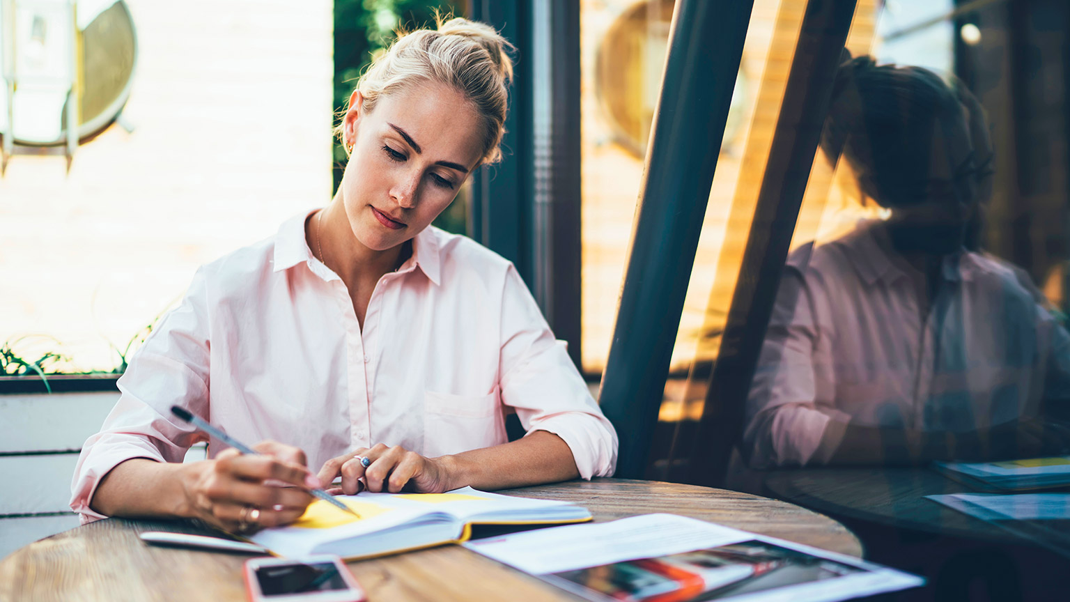 Professionally dressed female sitting at desk writing a business plan