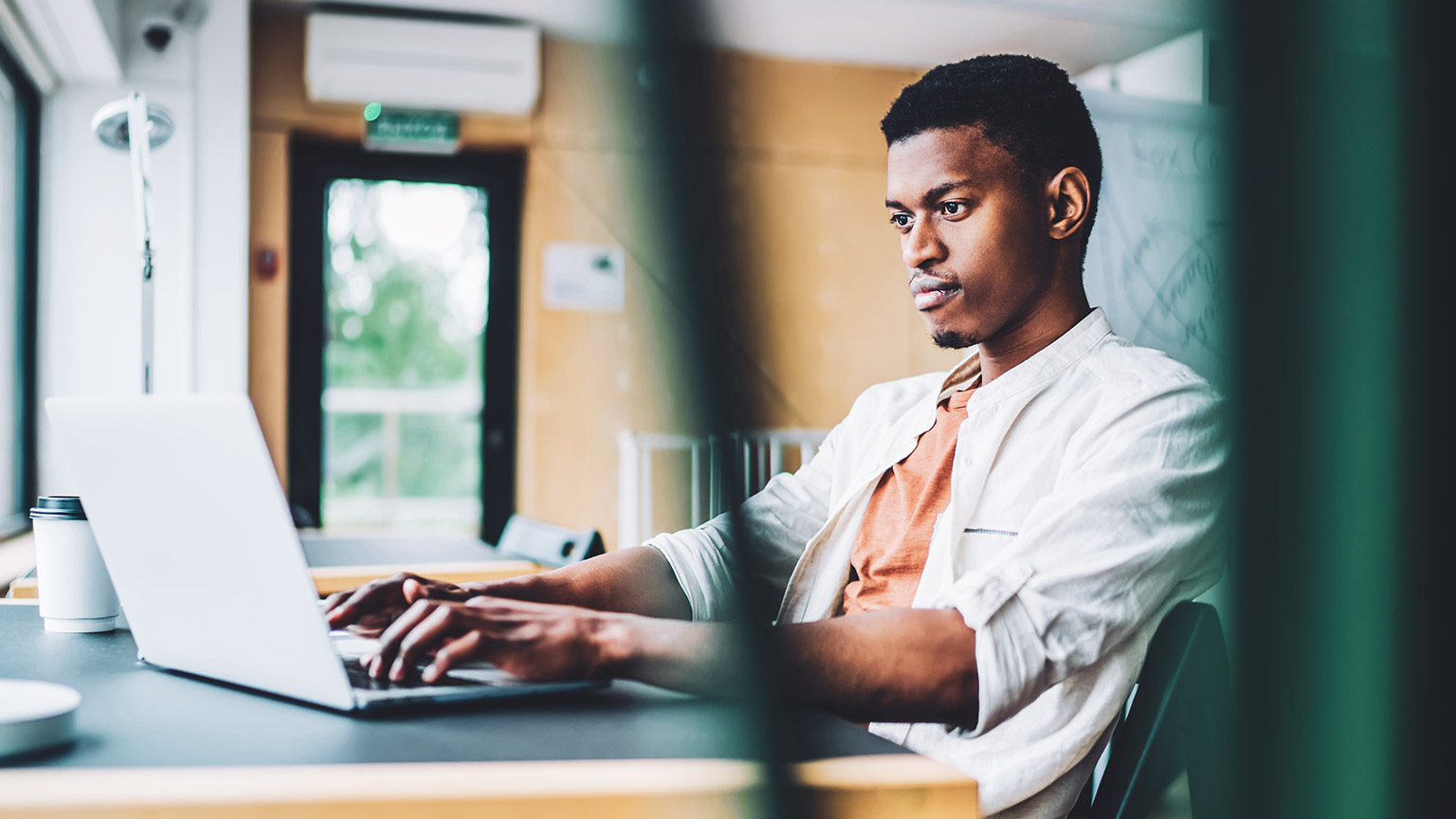 Male designer sitting at desk working on laptop