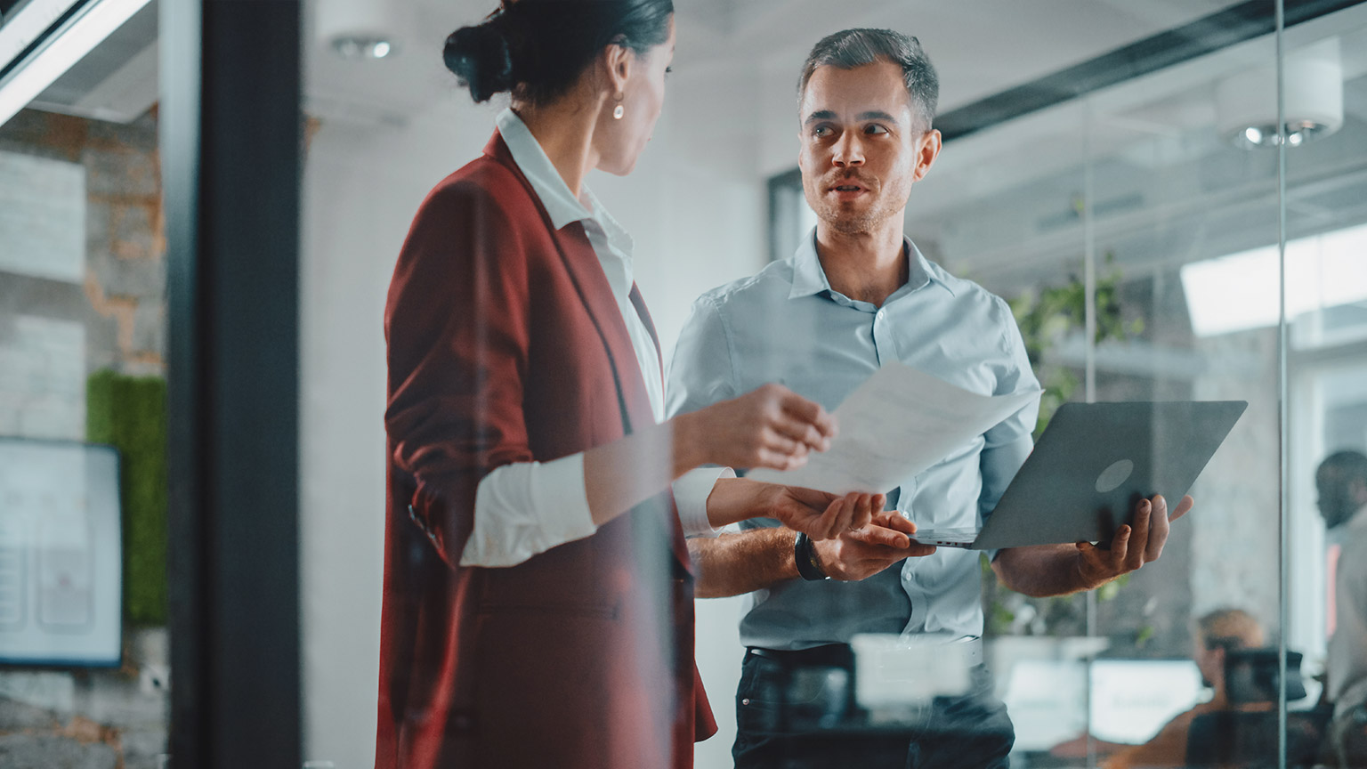 2 business professionals talking about business in a modern office environment