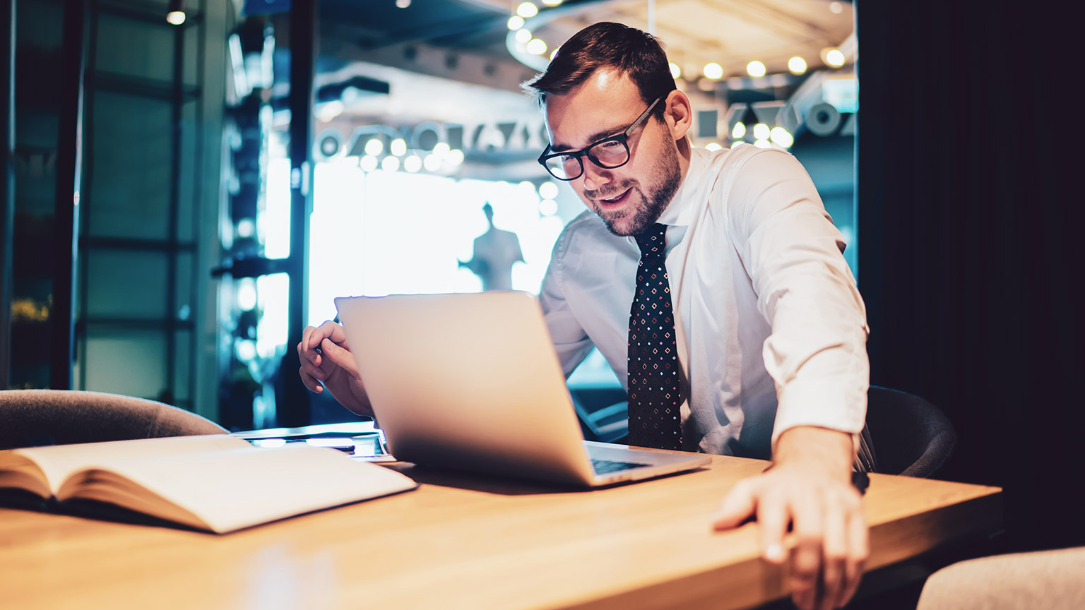 Business professional sitting at a desk looking at a laptop in a modern office