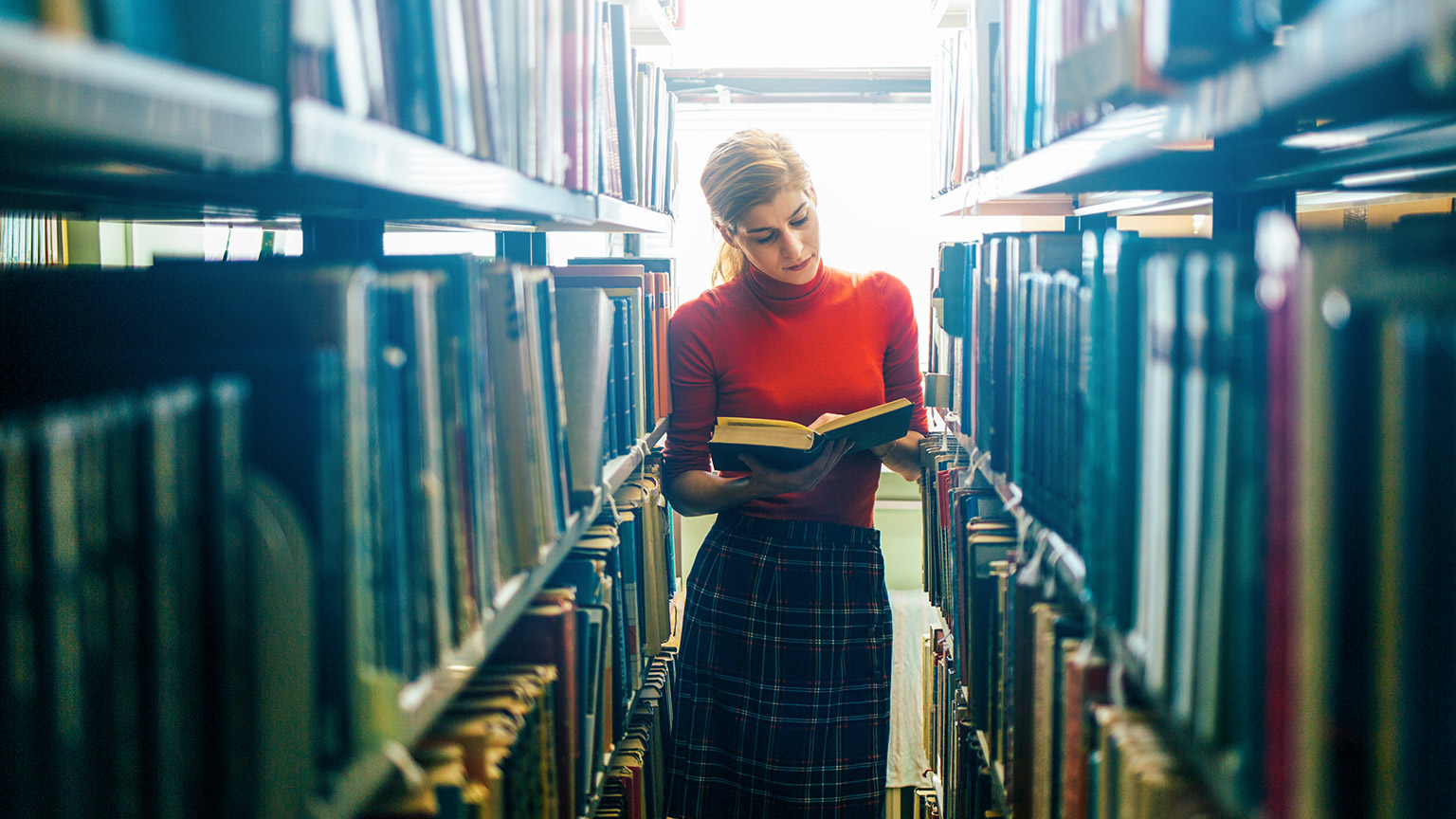 Young female reading book in a library