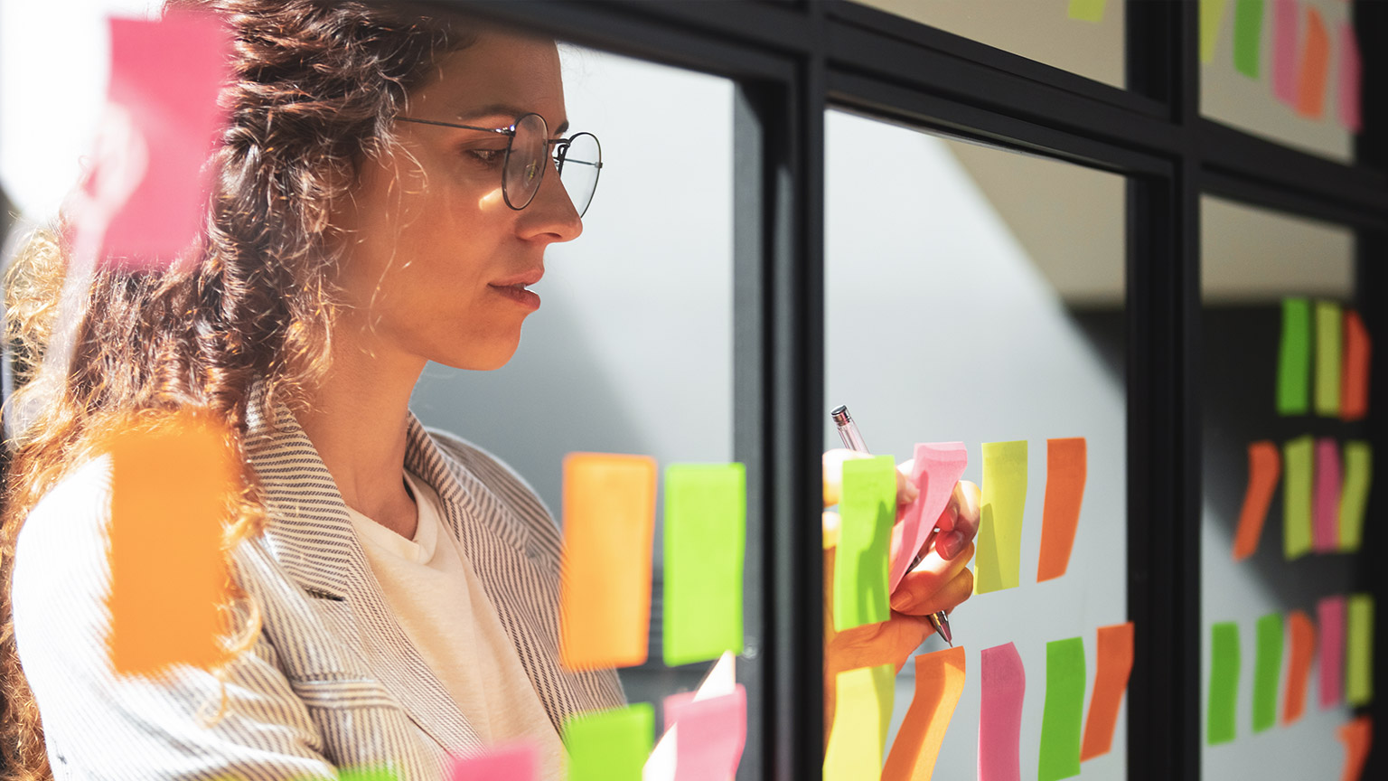 Close view of woman arranging sticky notes on glass window of office