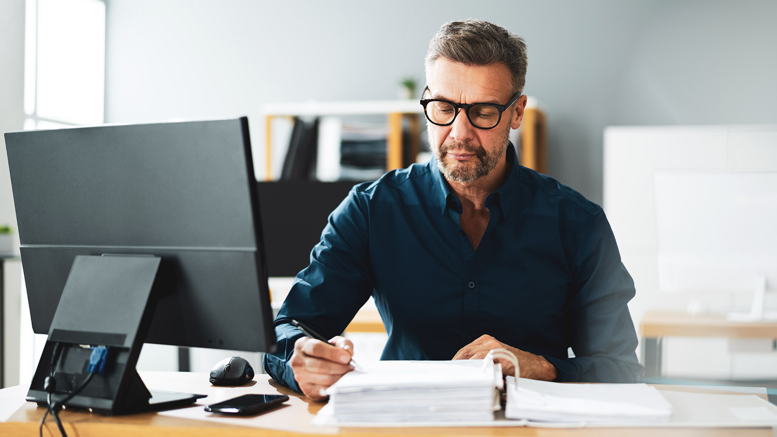 A construction supervisor sitting at a desk in an office finalising the paperwork on a construction deal