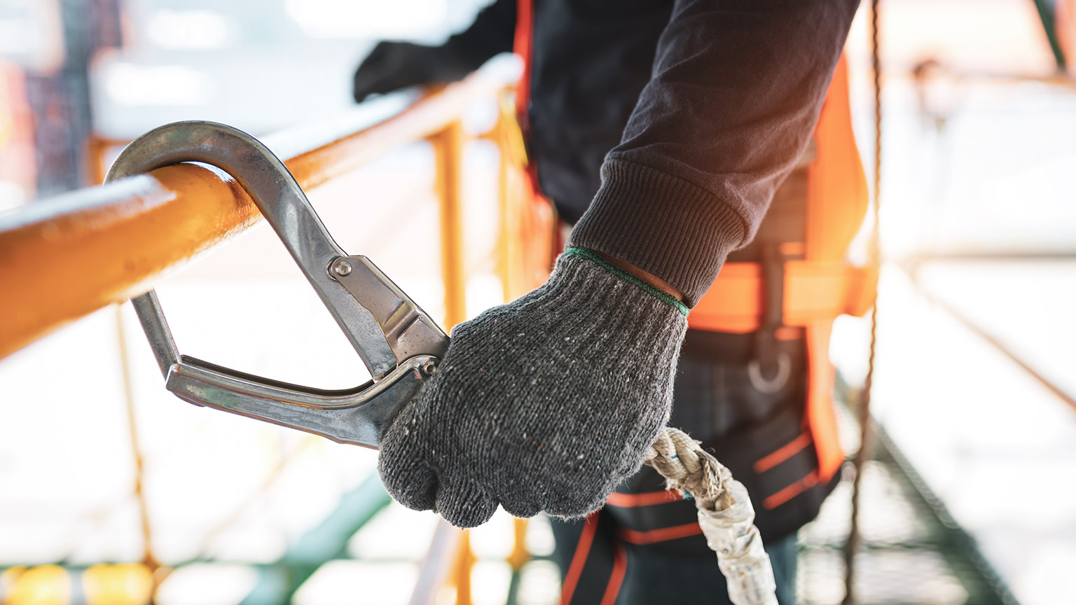 A close view of a construction worker clipping a safety belt onto a rail