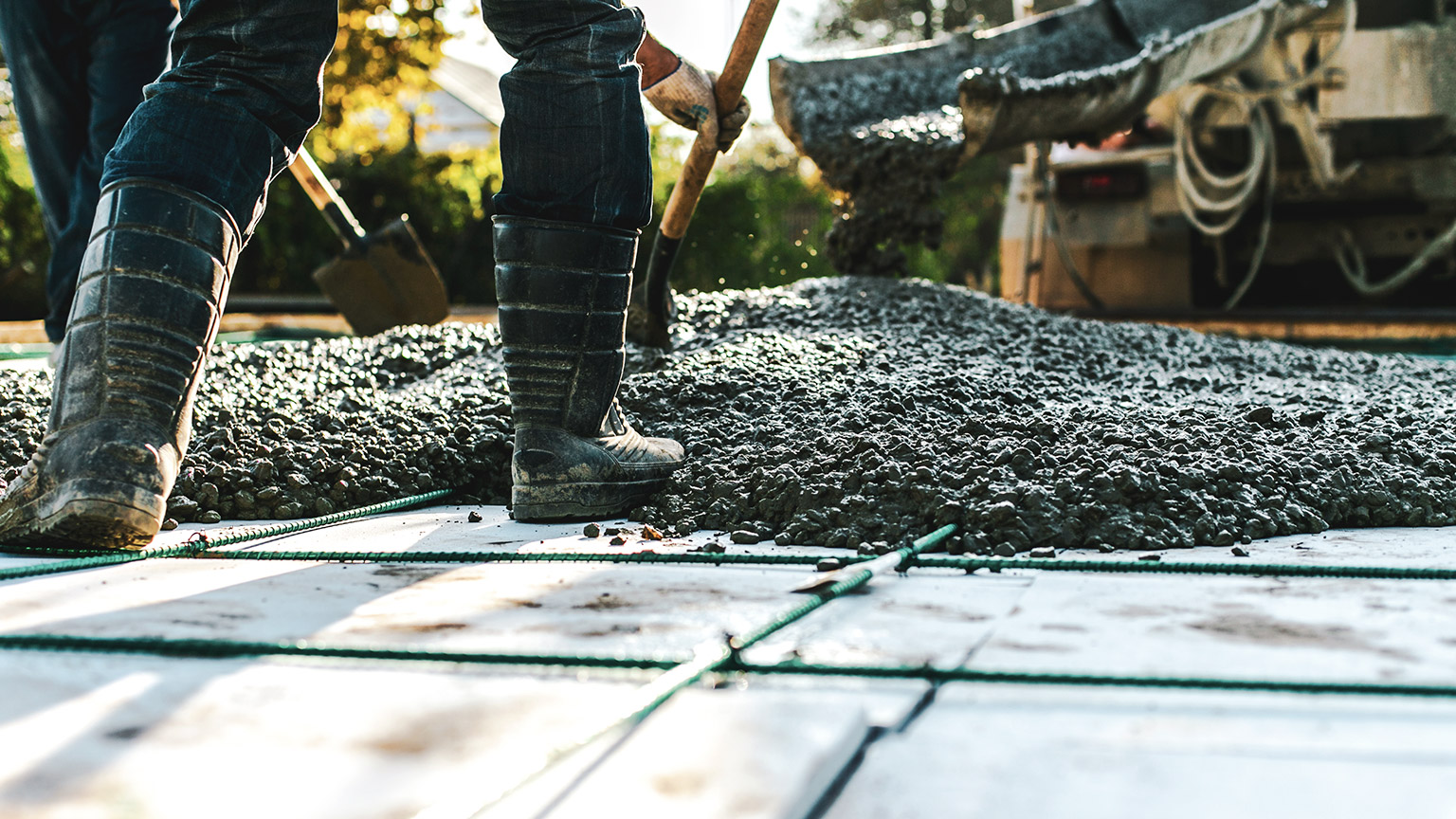 A low angle view of construction workers spreading freshly poured concrete on a building site