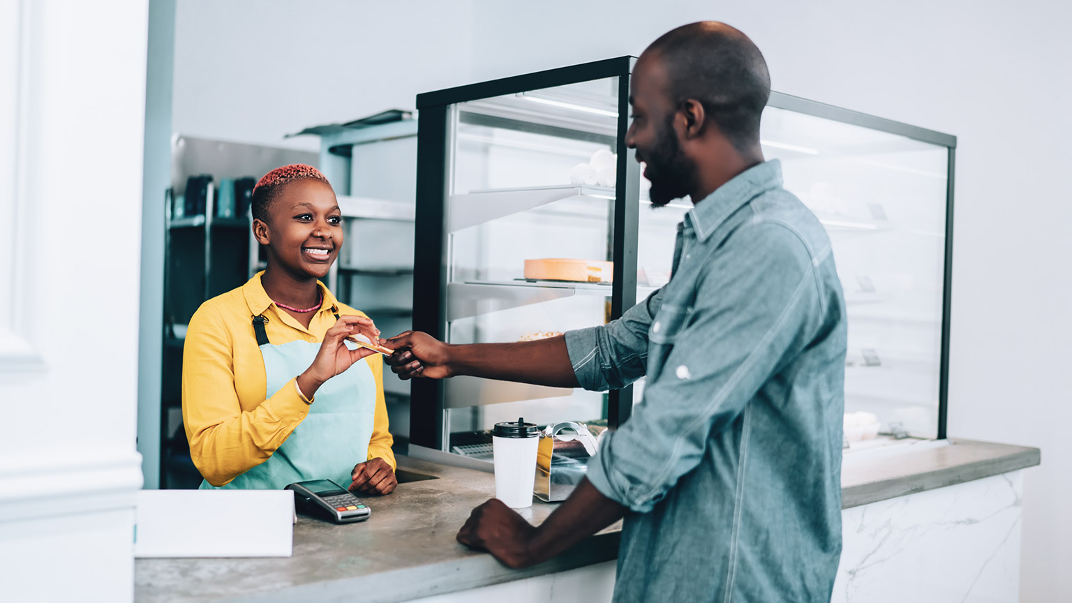 A smiling business owner serving a customer at her cafe