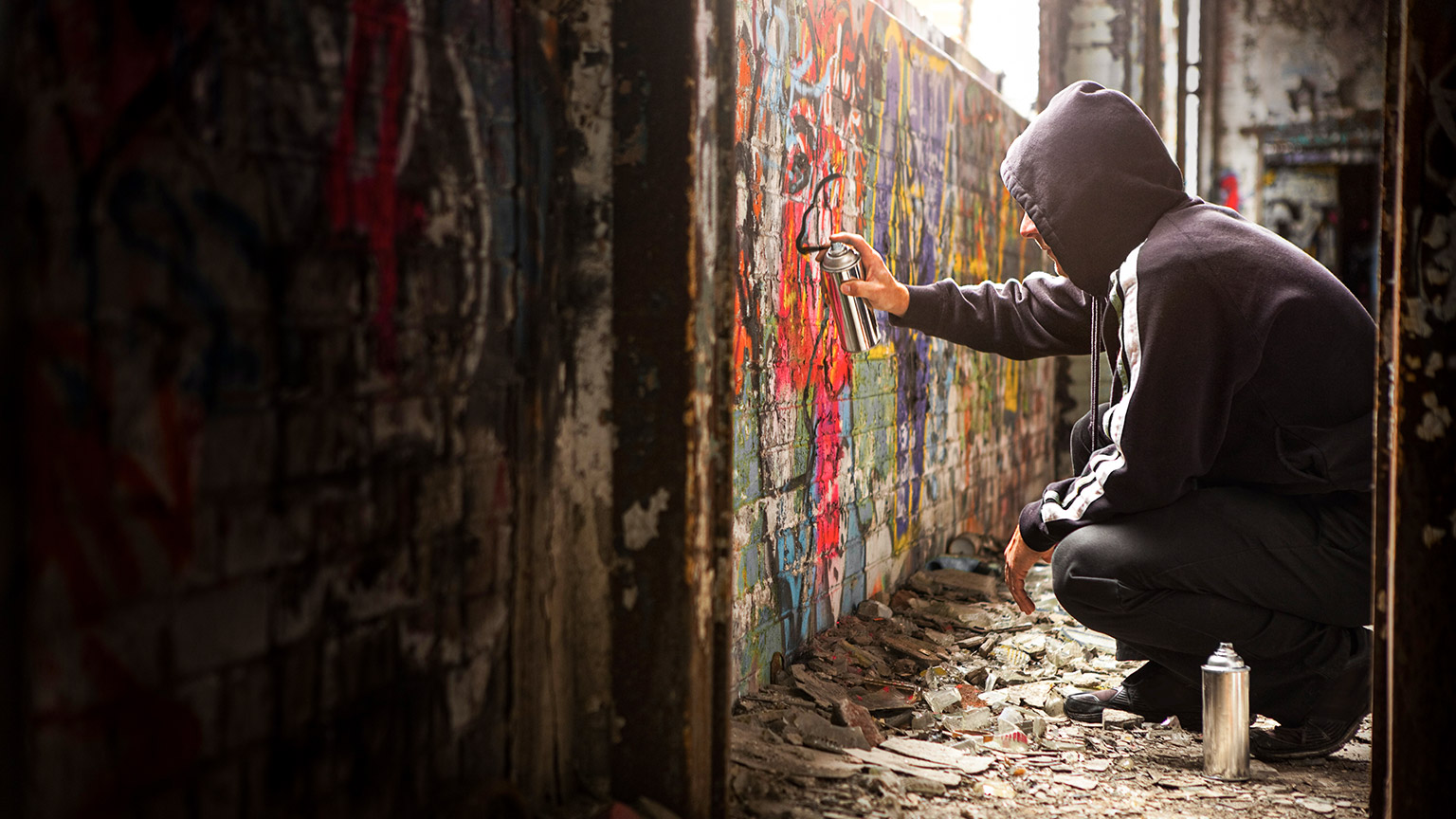 A young person tagging a derelict brick wall