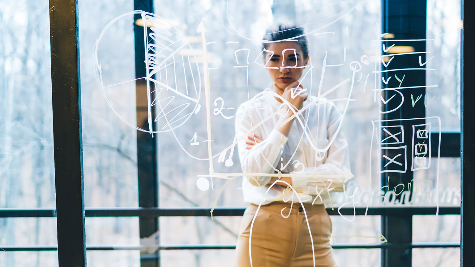 A business developer staring pensively at a complicated web of diagrams on a glass wall