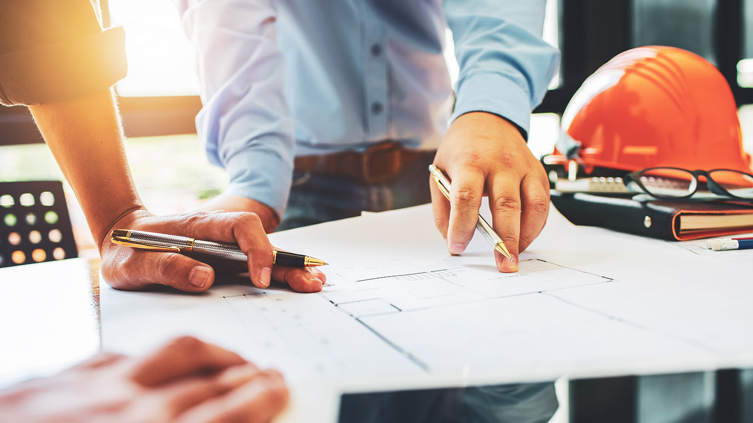 An engineer and a project manager at a desk, discussing their work schedule