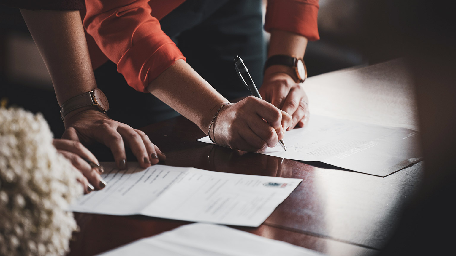 Two business people signing a contract on a table