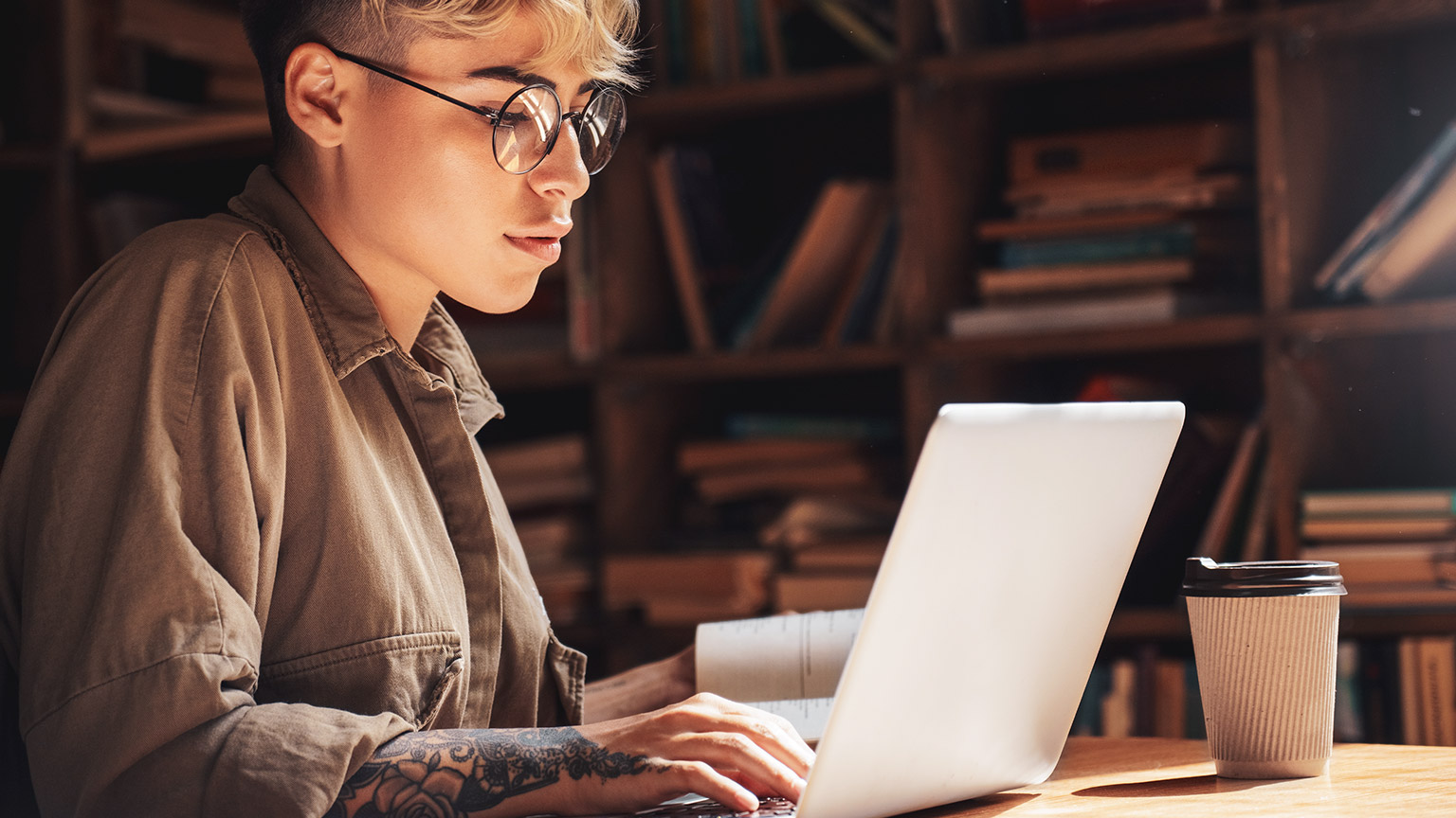 A young business sitting in a library reading resource material on a laptop