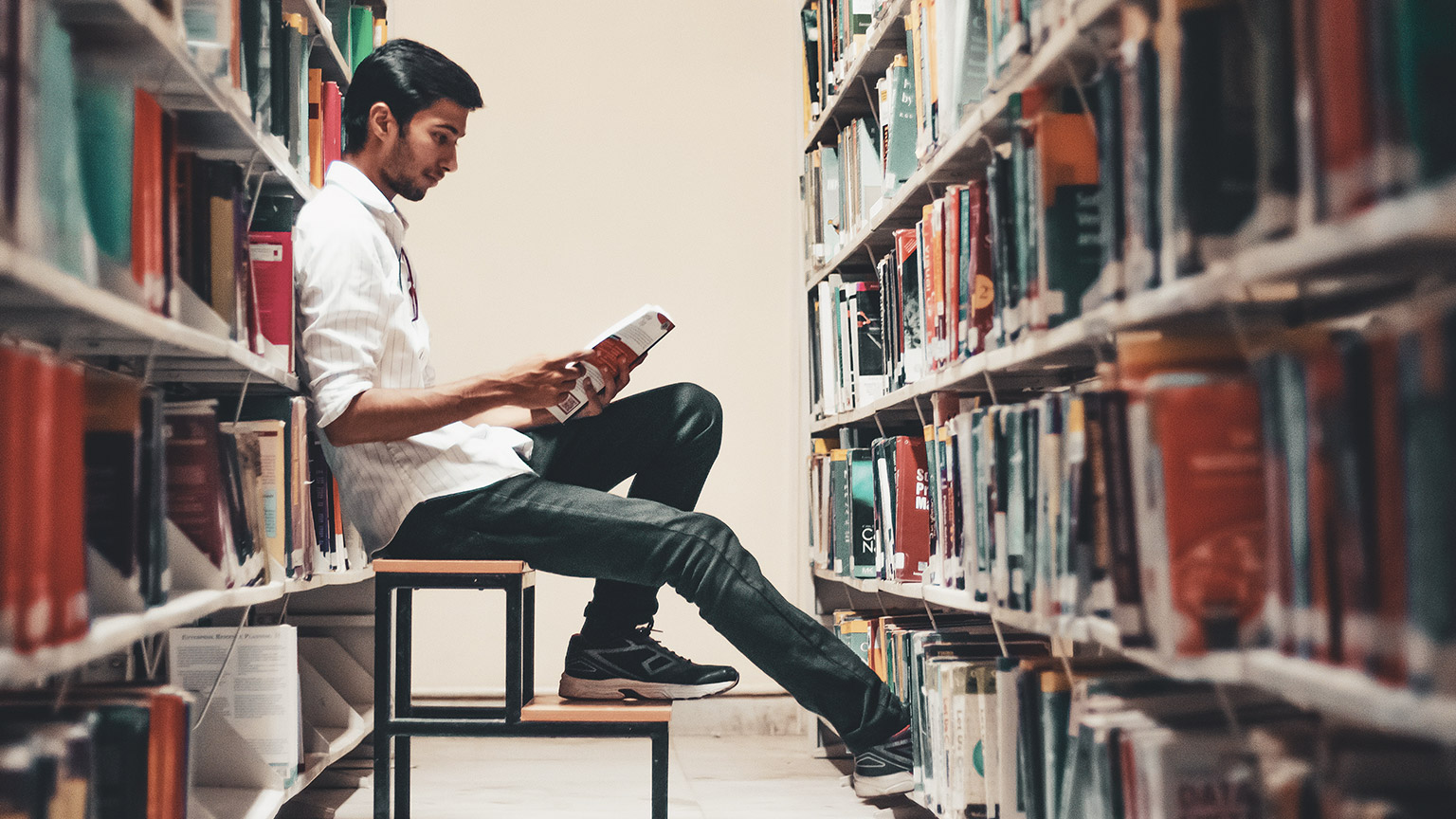 A student sitting in a library reading a book