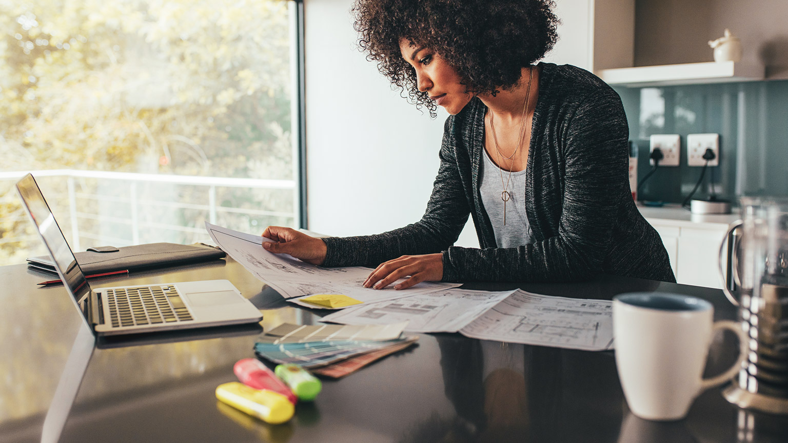 A professional looking over project materials at a table in a modern office space