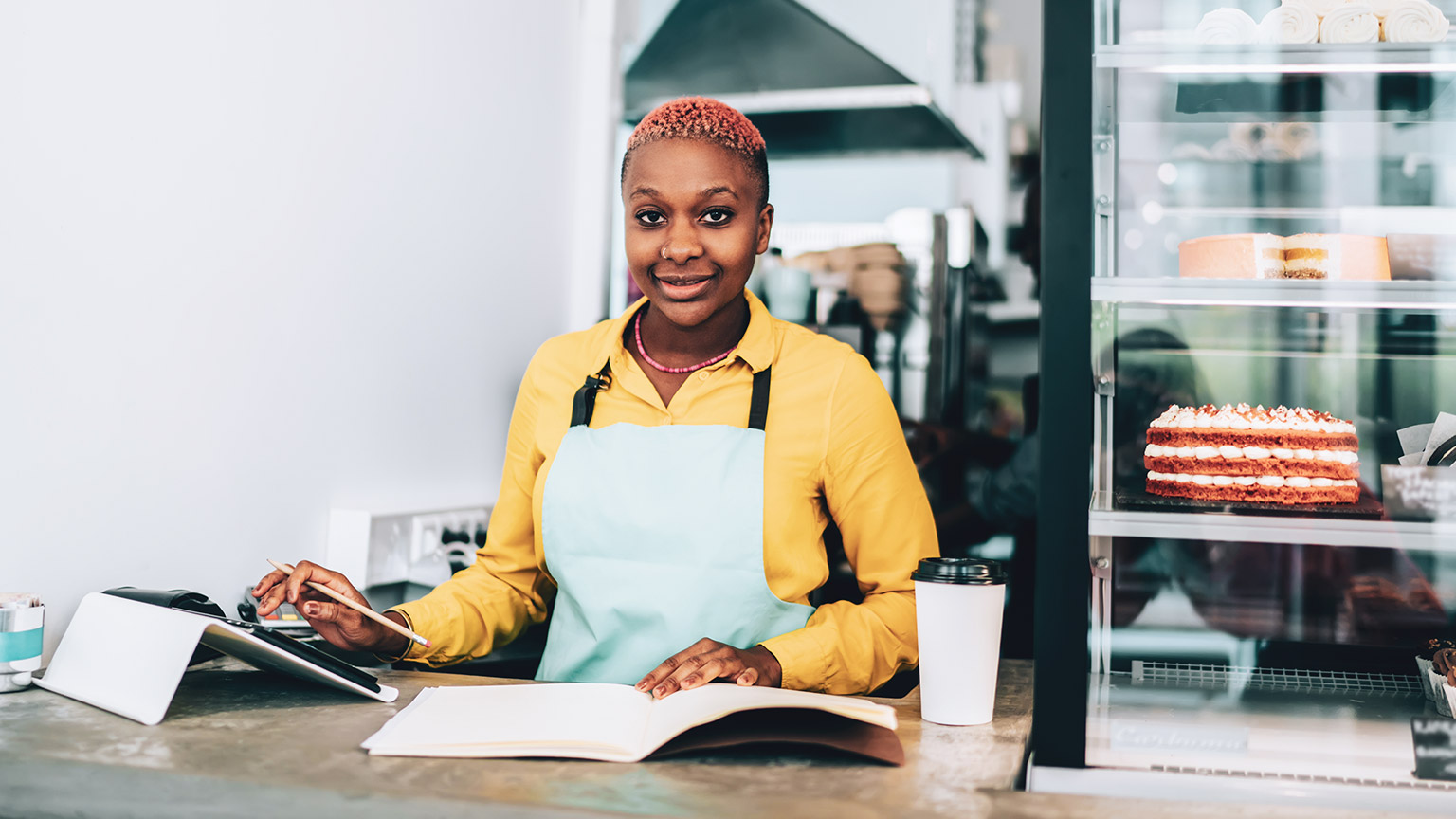 A smiling business owner doing calculations at the front counter of her shop