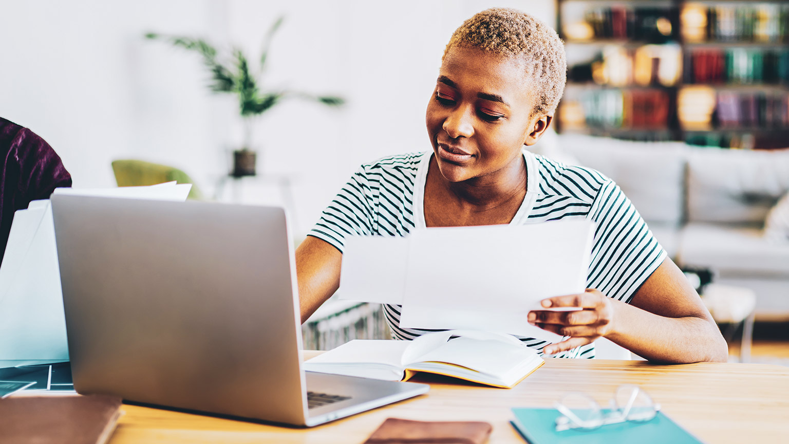 A business person reading source material while sitting at a desk with a laptop