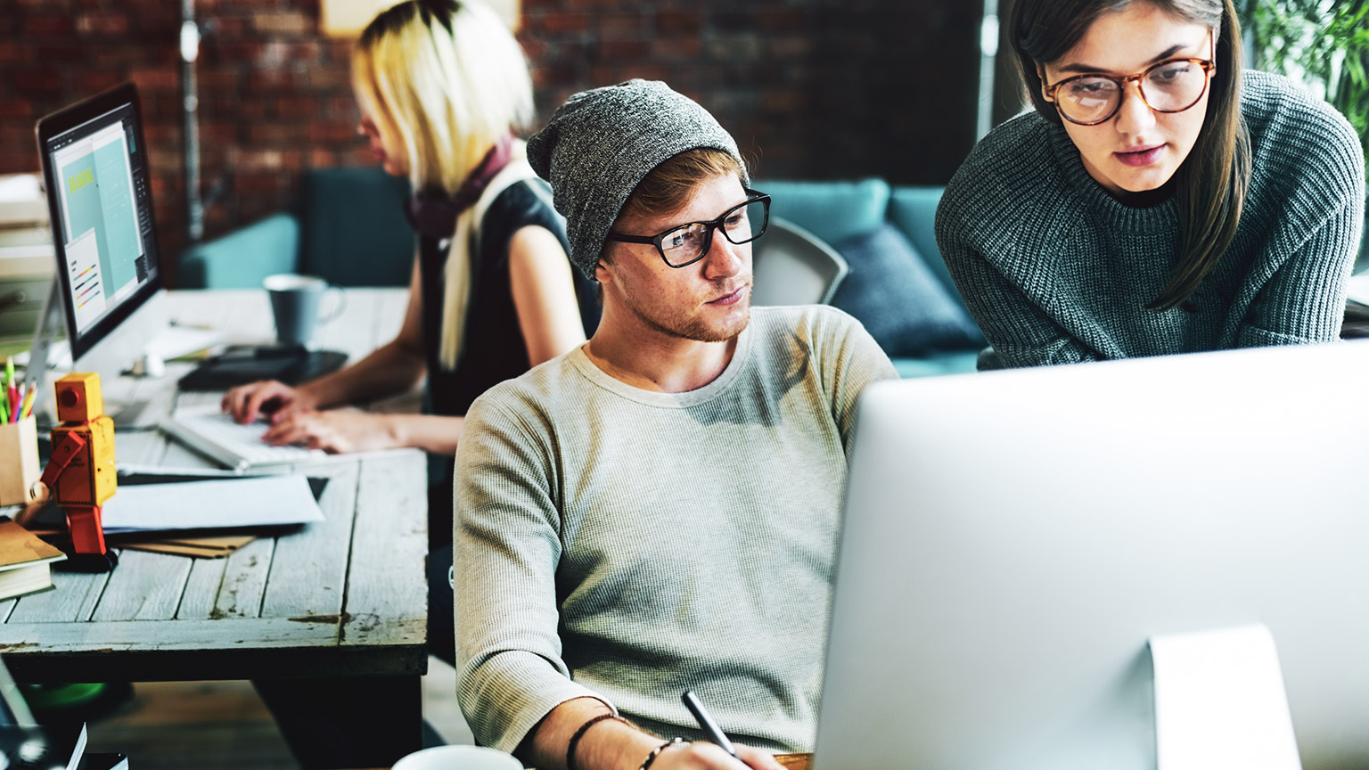 Three designers in an office working on design projects