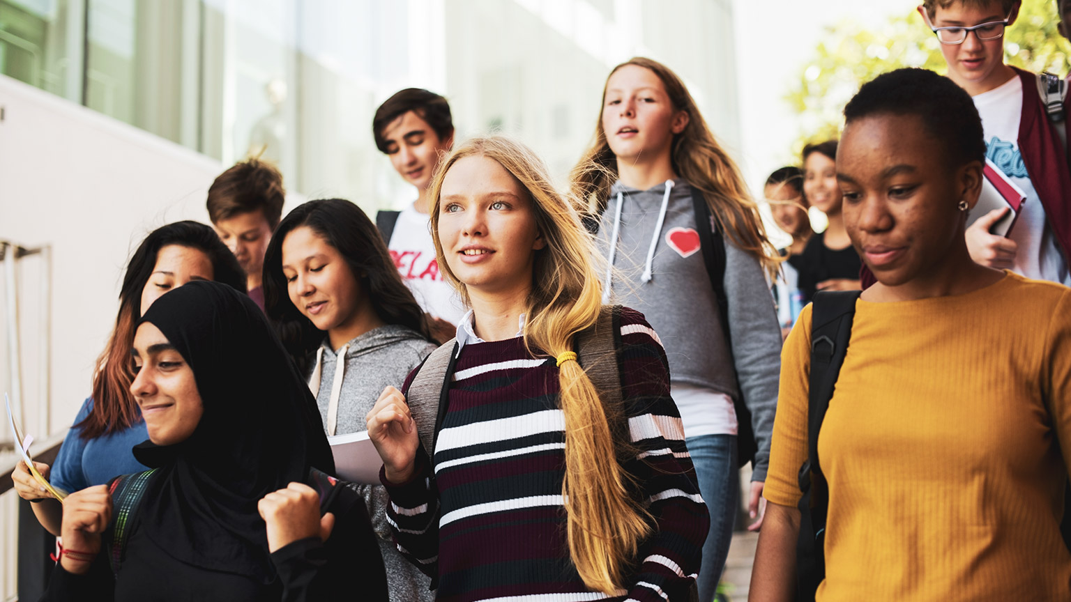 A diverse group of teenage students walking down stairs