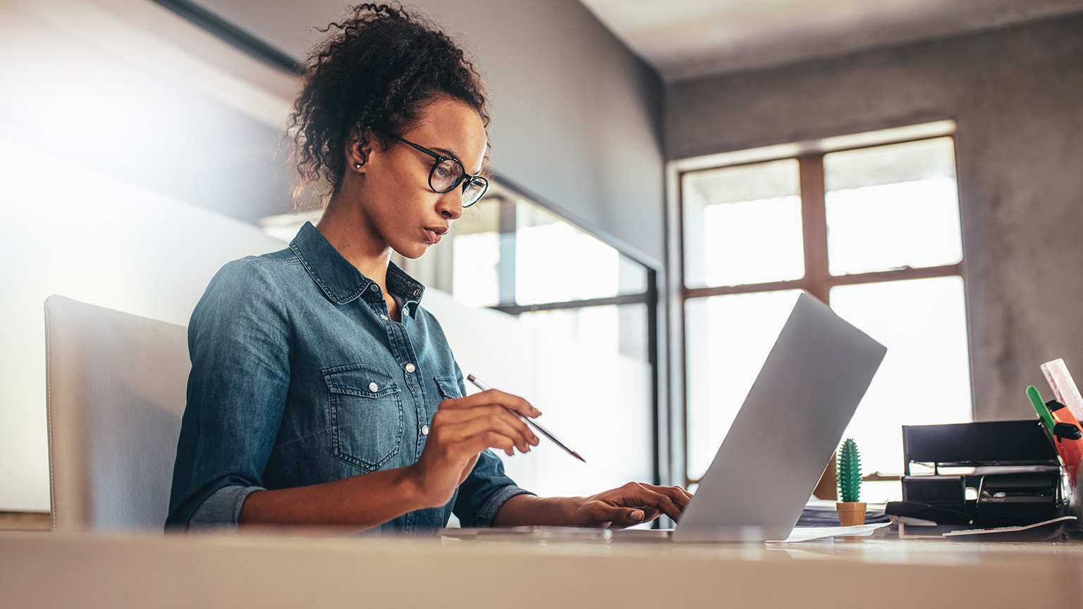 A young business person focussed on their laptop as they create a business document