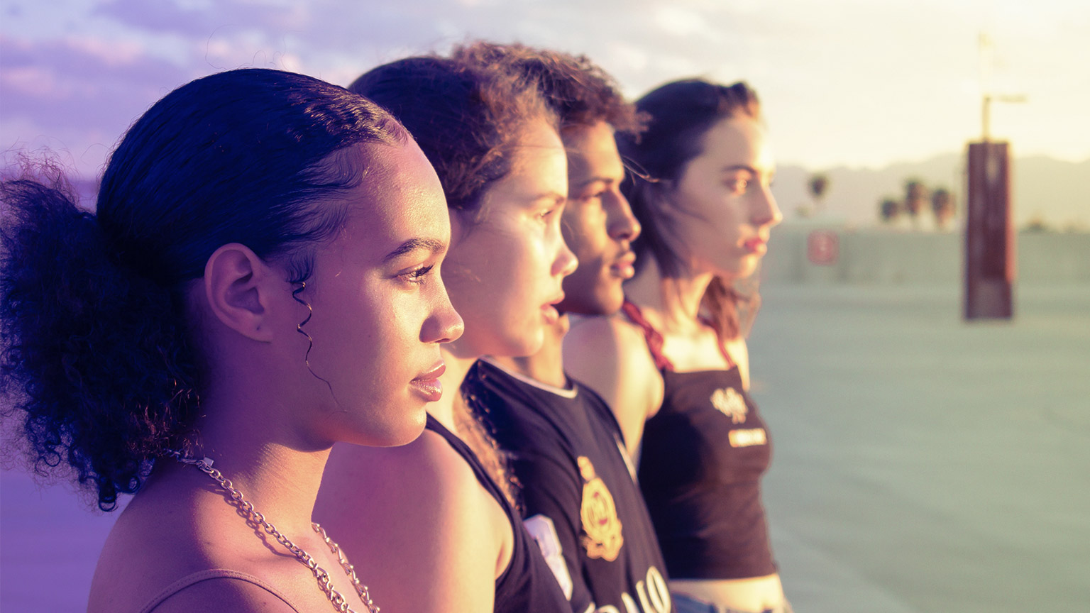 A group of teenagers at the beach facing toward the setting sun