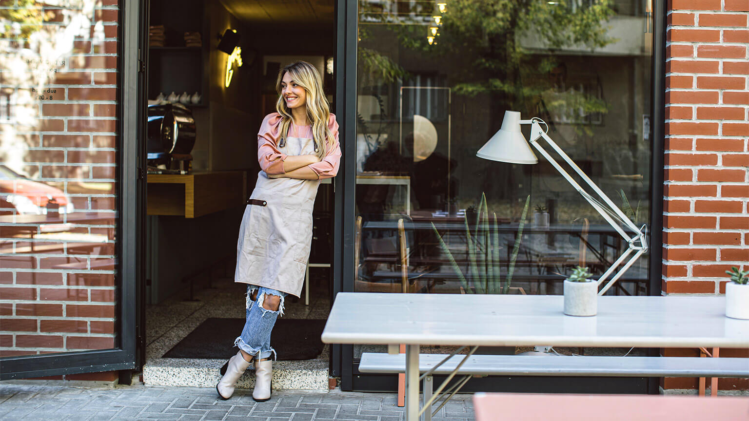 A business owner leaning in the doorway of their business