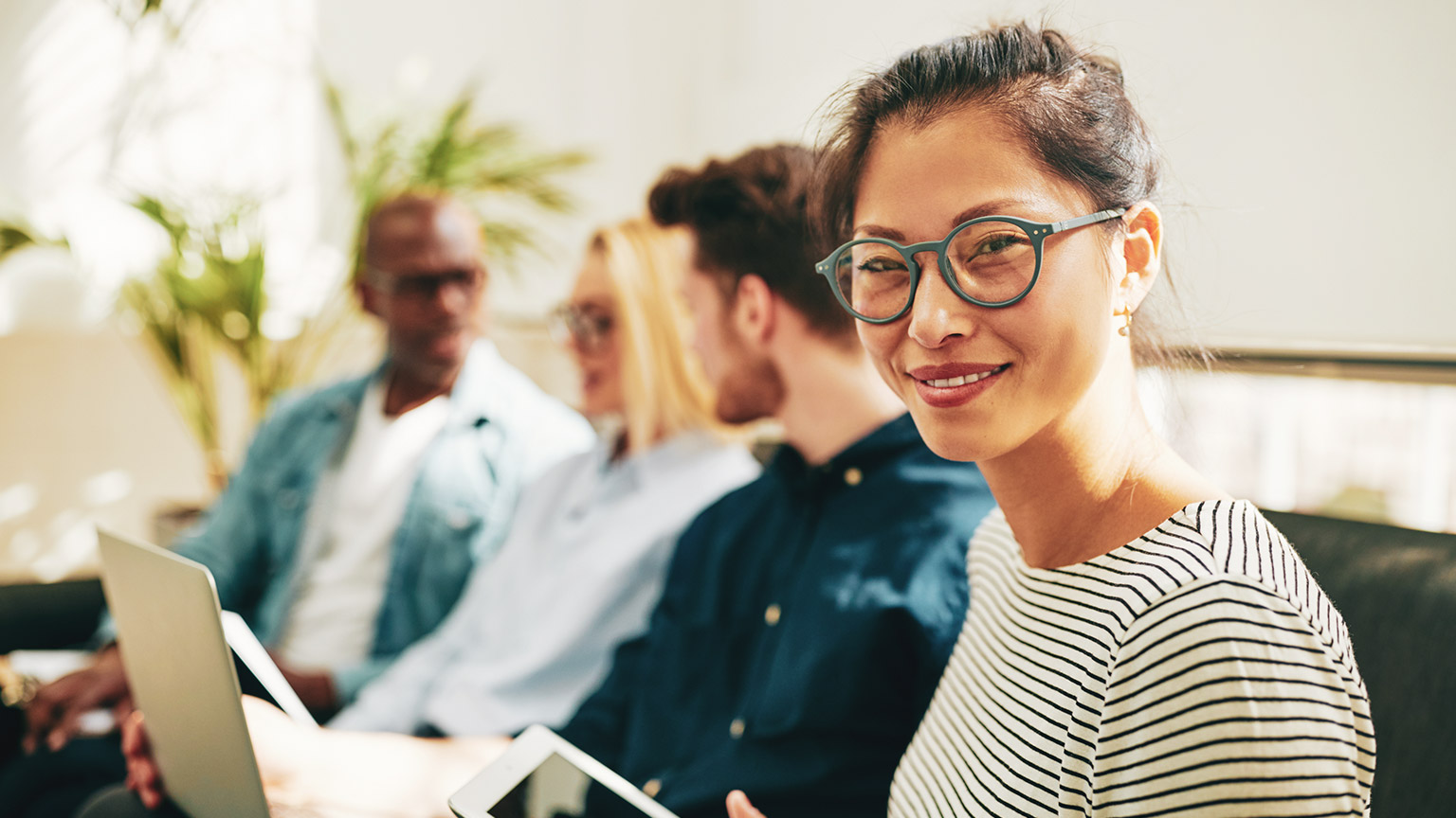 A smiling business professional with several coworkers visible in the background