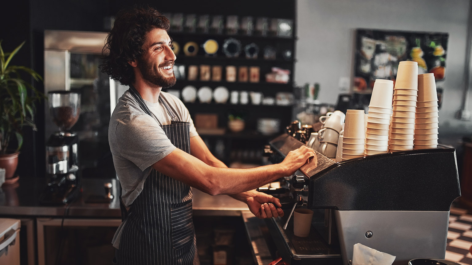 A smiling barista enjoying his customer service role