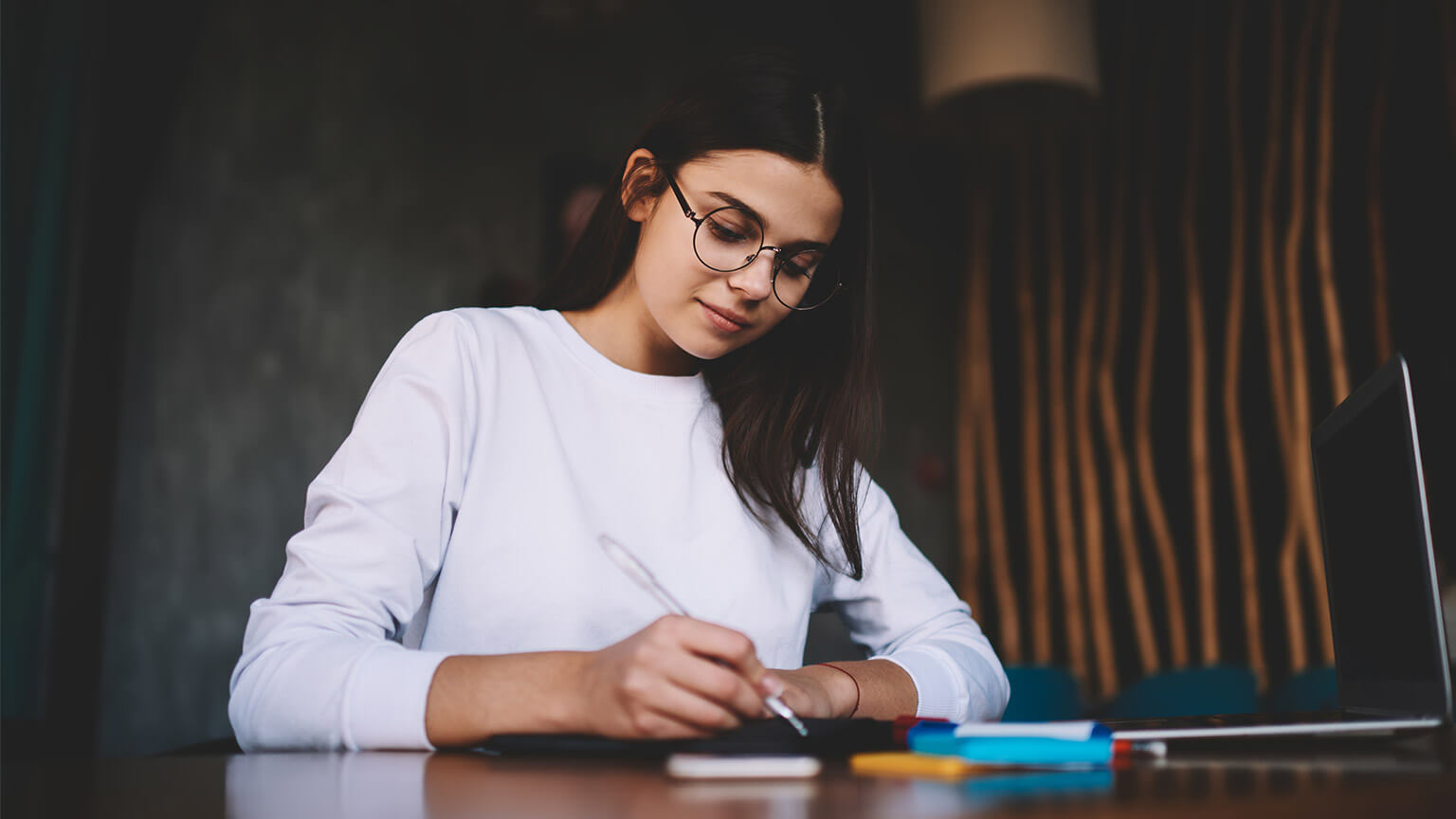 A student seated at their desk, taking down notes