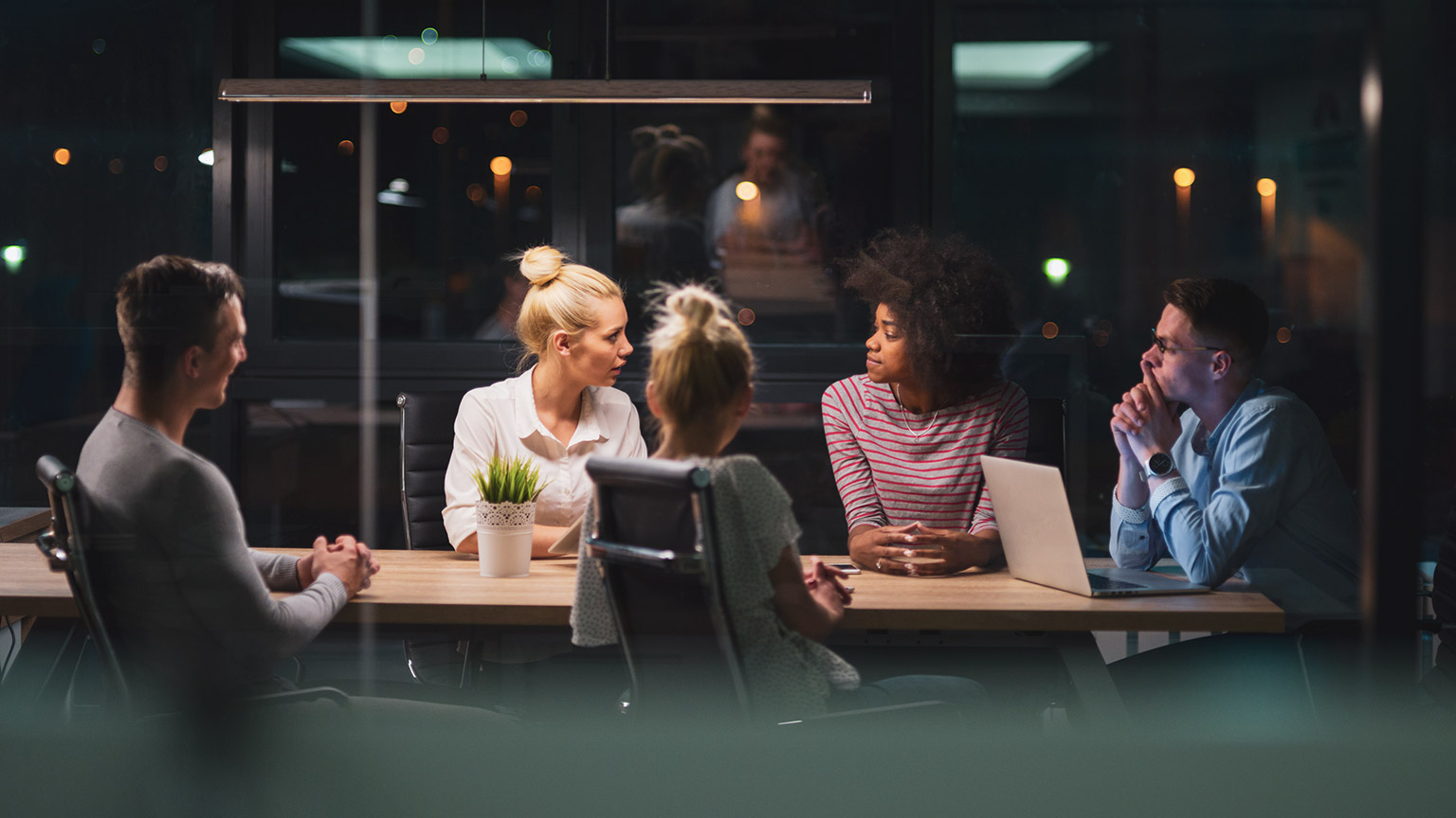 A group of young business professionals discussing a work project in a meeting room in a modern office