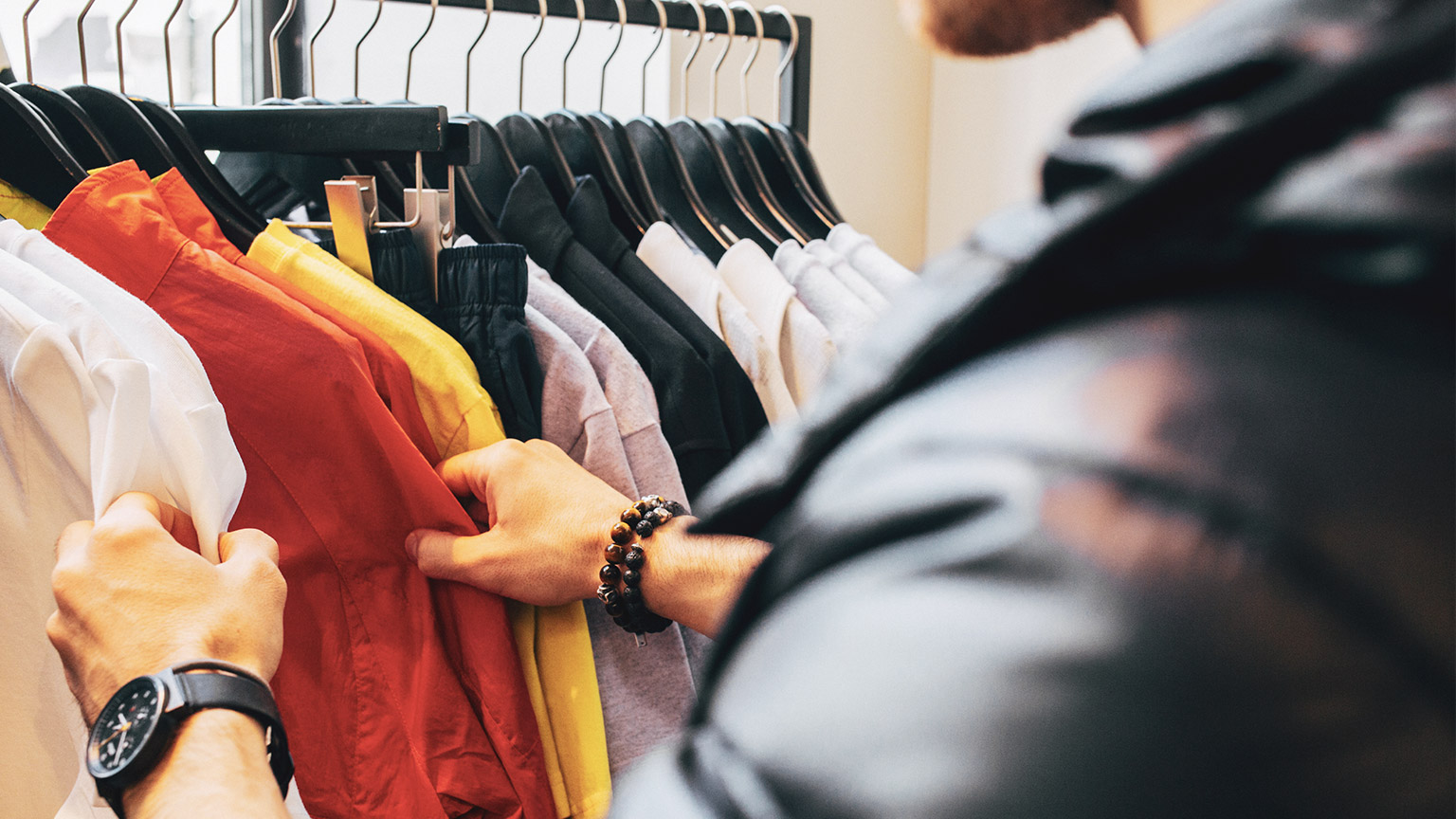 A close view of a shopper browing through a rack of shirts