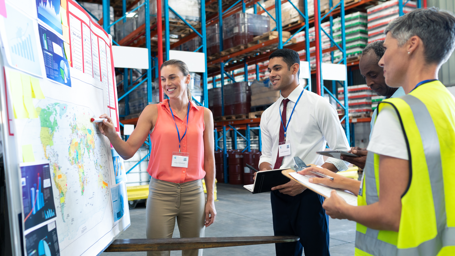 Front view of diverse warehouse staffs discussing over whiteboard in warehouse. This is a freight transportation and distribution warehouse. Industrial and industrial workers concept