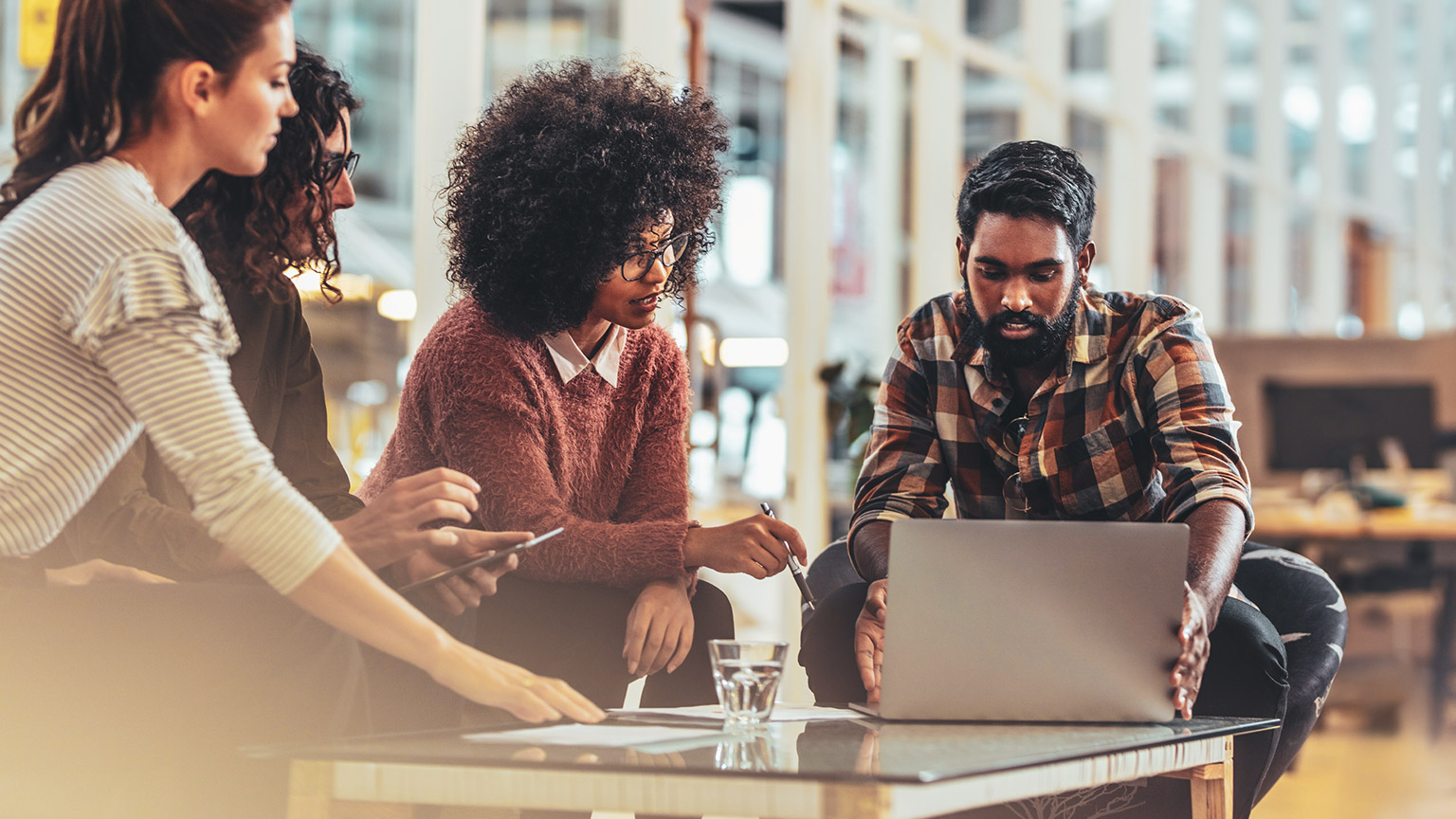 A group of coworkers watching a product demonstration on a laptop