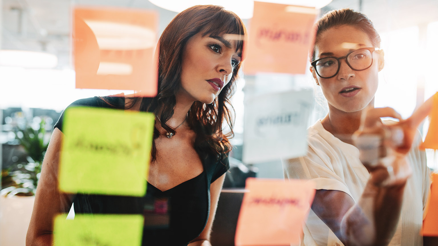 A pair of marketing executives mapping out a job on sticky notes