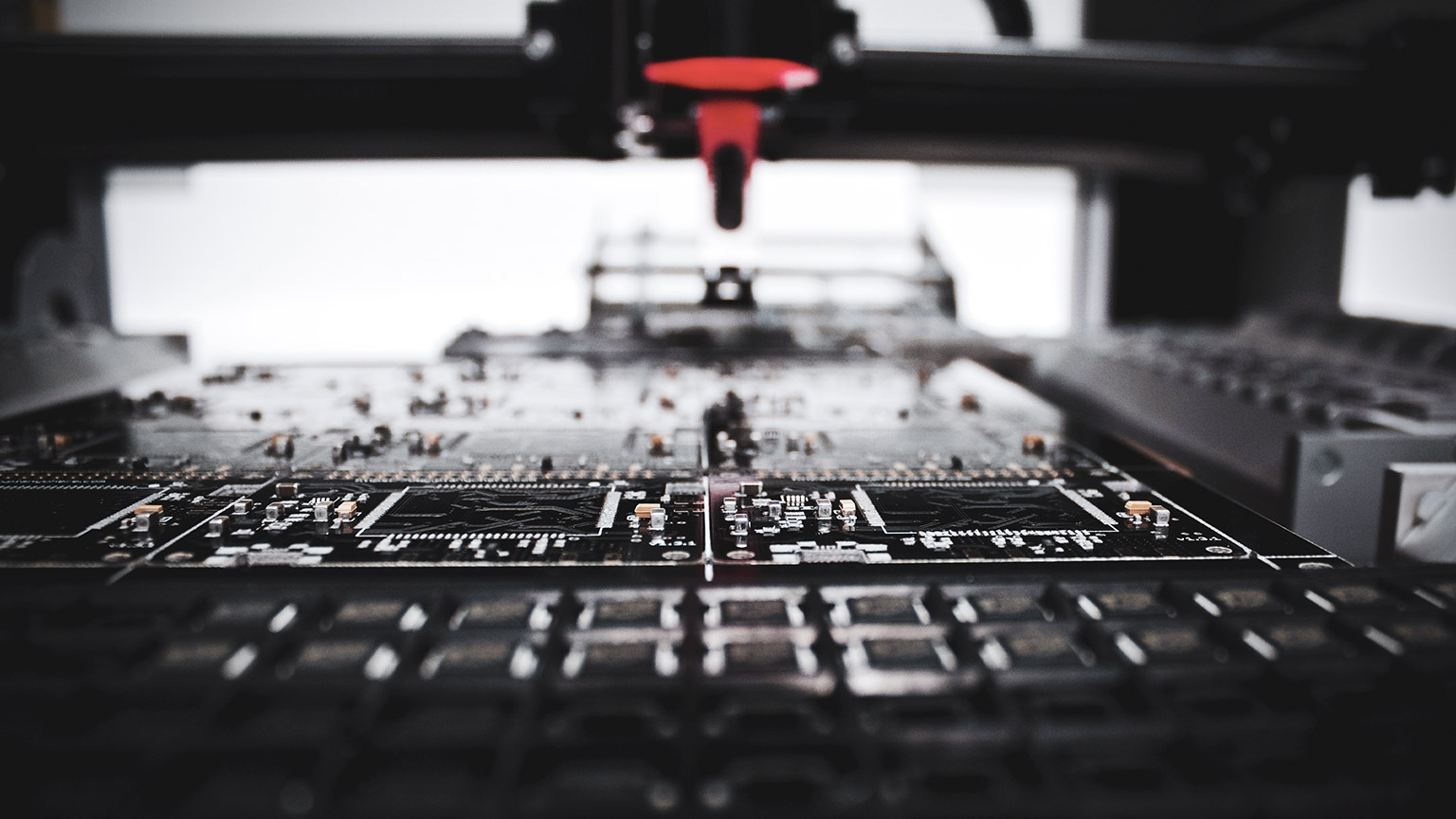 A close view of a machine assembling complex electronic circuitry