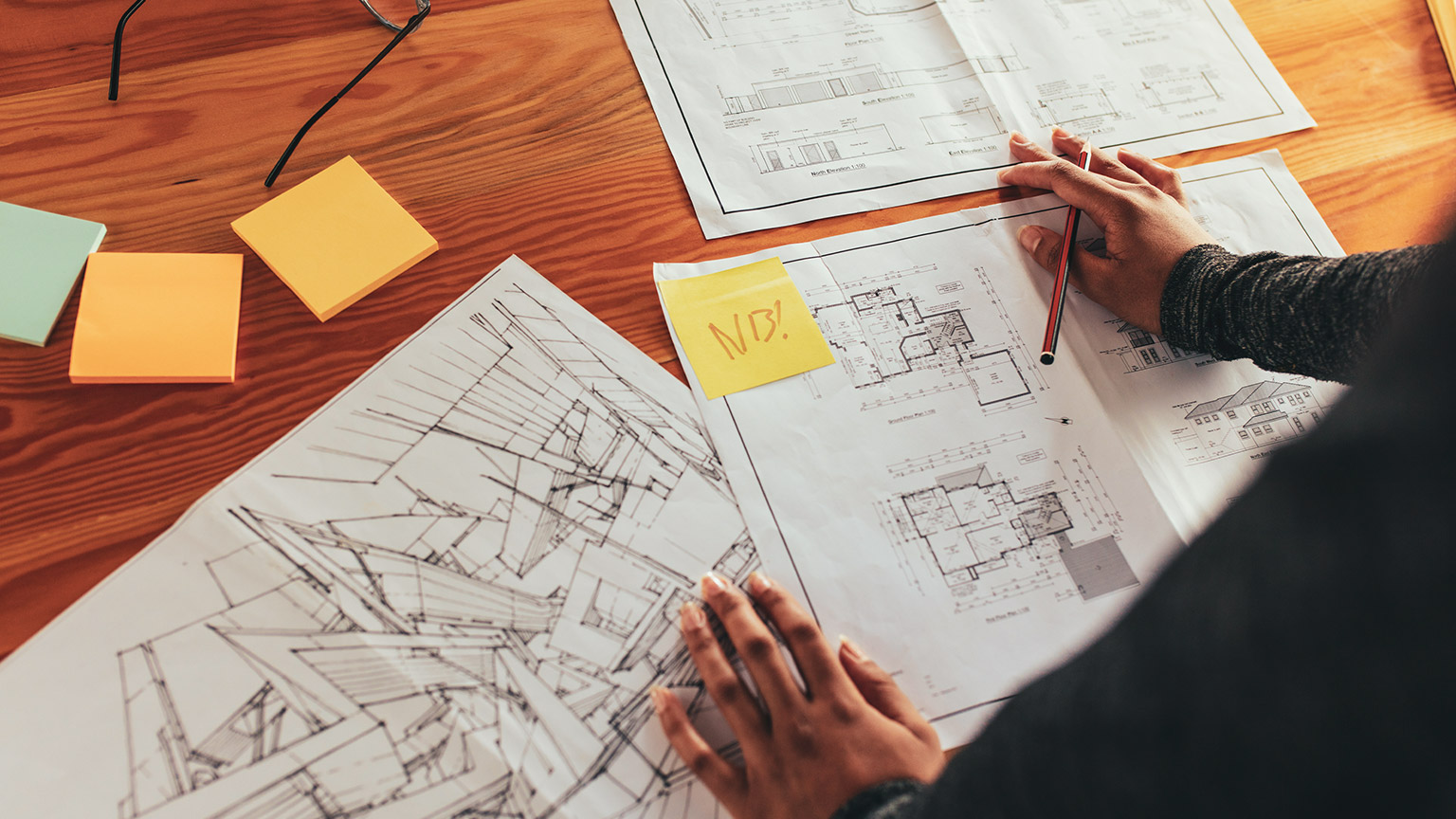 Over the shoulder view of a construction manager consulting multiple building plans