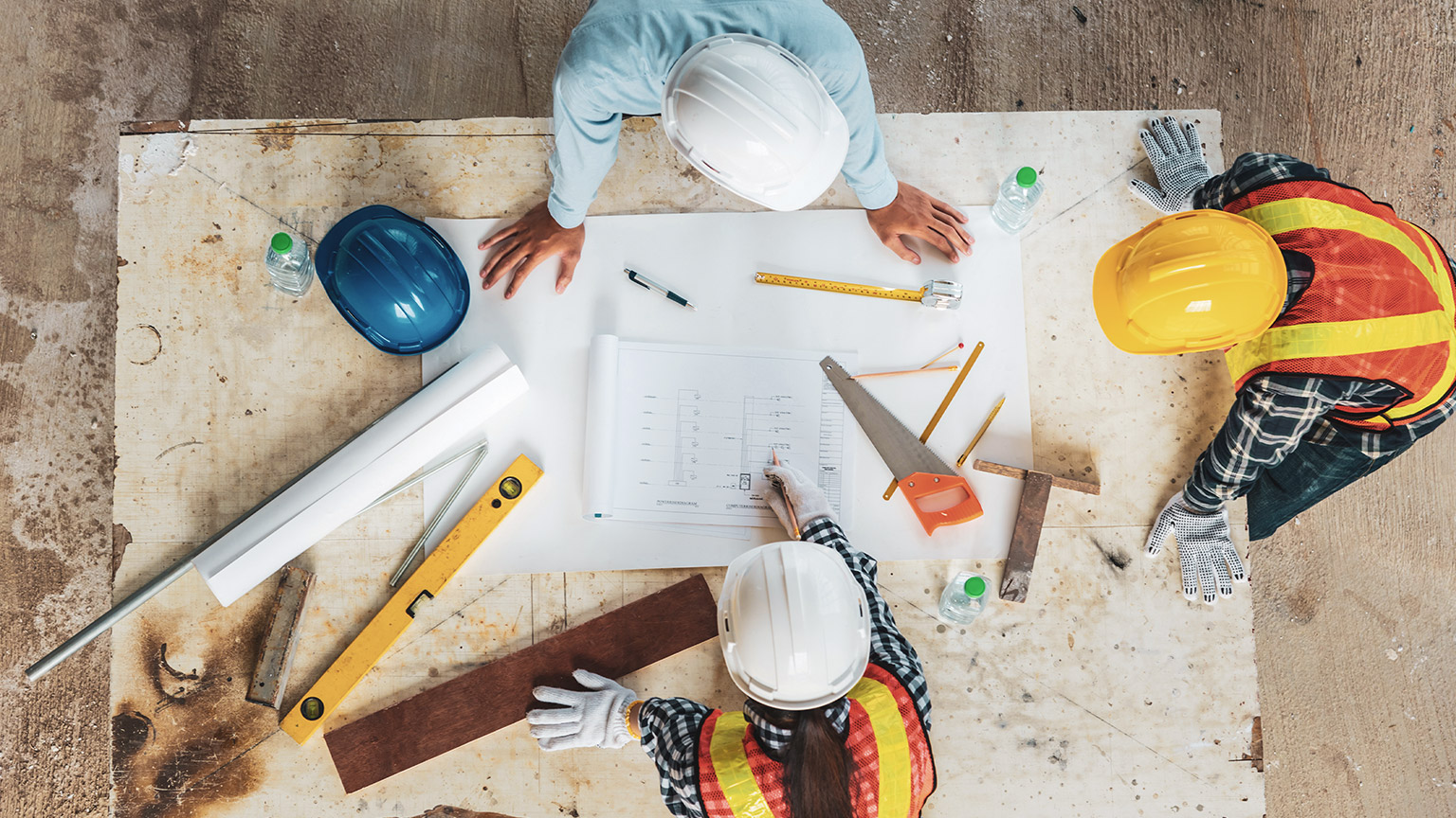 A group of construction managers consulting a plan on a table at a building site