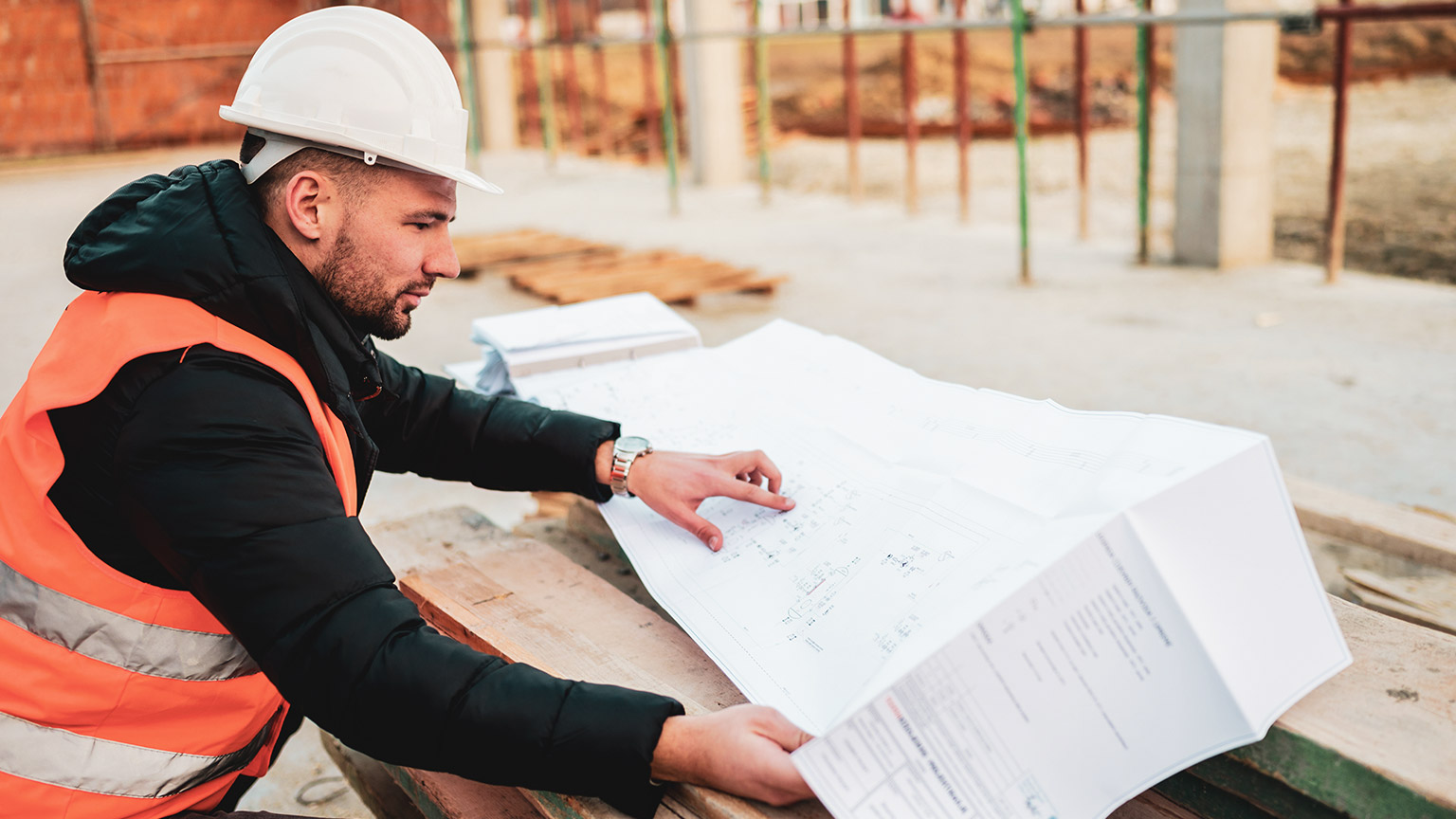 A construction manager consulting plans while working on a building site