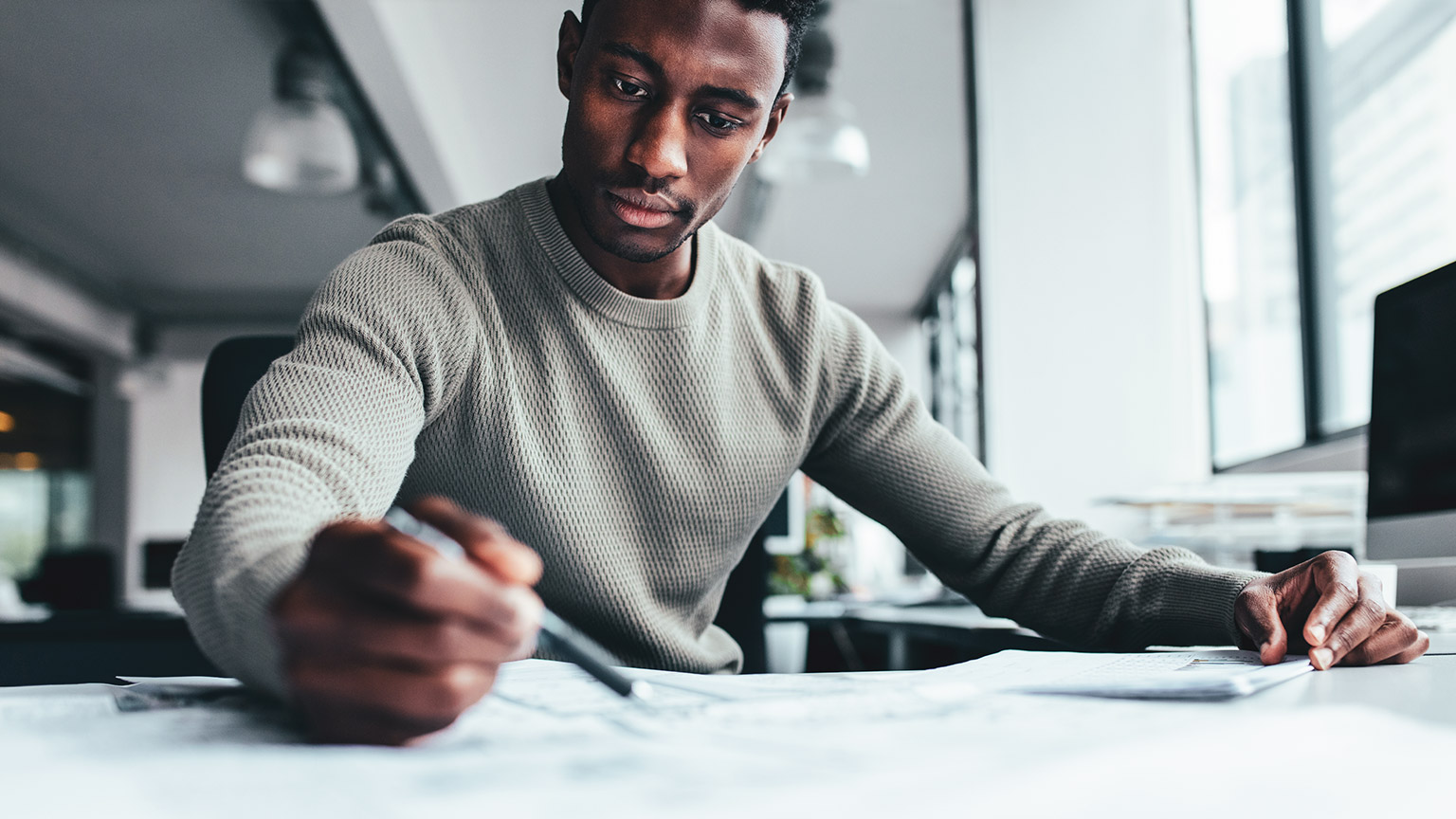 A young professional looking over construction plans in a modern office