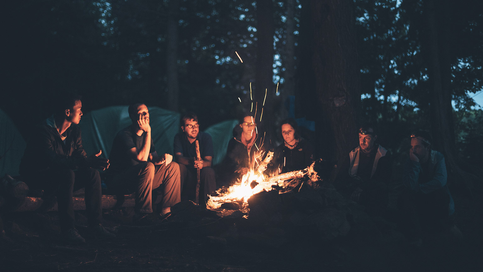 A group of youth workers and youth sitting around a fire