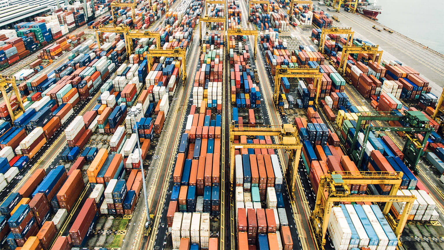 An aerial view of a large, colourful container yard at a busy port