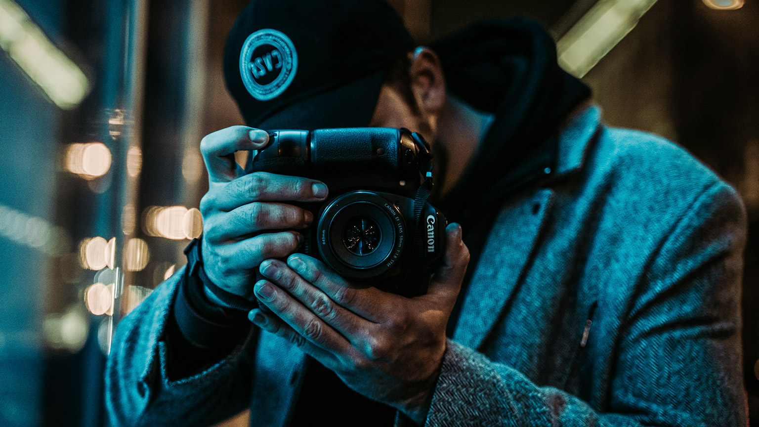 A close view of a photographer shooting with a Canon DSLR at night