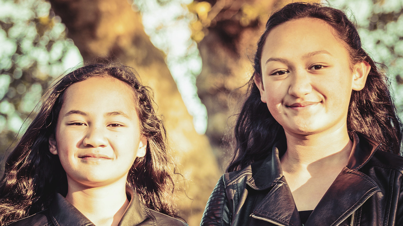 2 girls of Pasifika heritage smiling at the camera in an outdoor setting