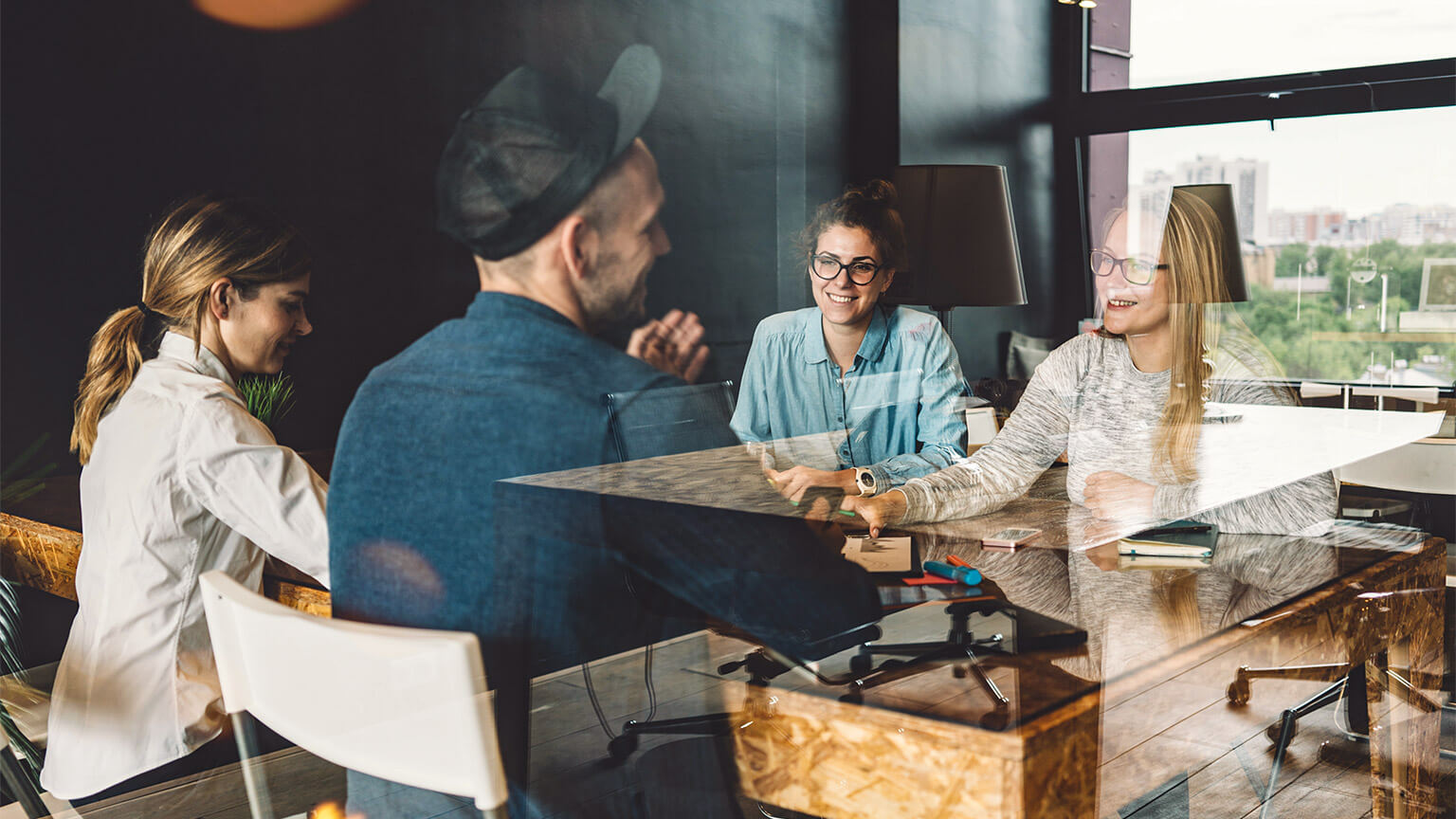 Team members holding a casual meeting with a client, in an open-plan office